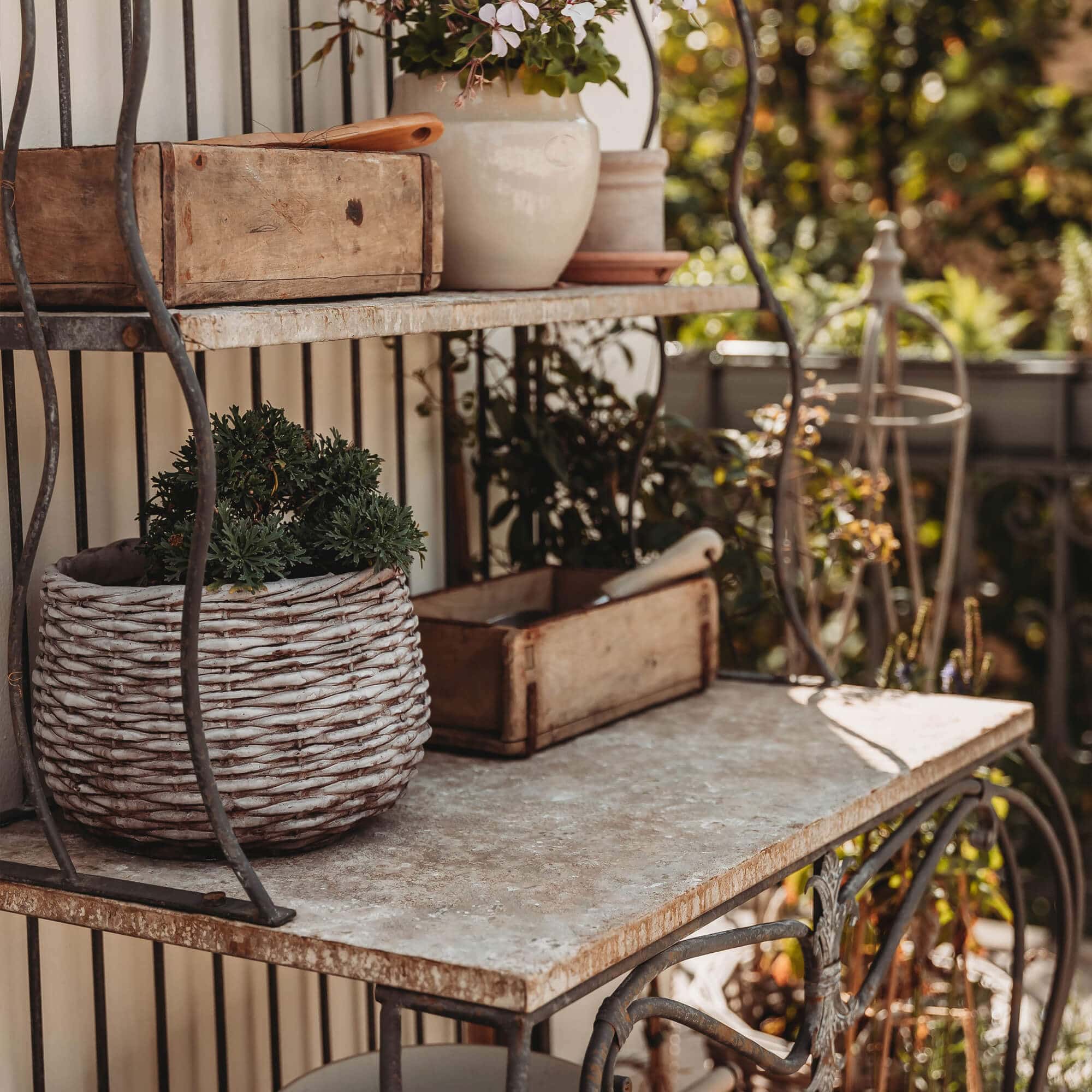 Scaffale in metallo con piano in pietra e cesta di vimini con pianta verde sulla terrazza