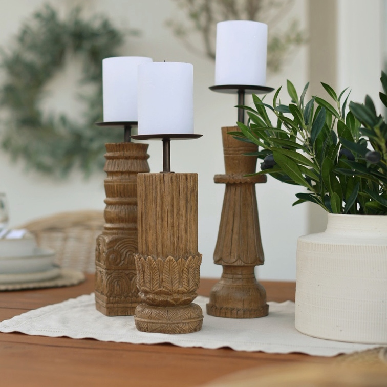 Tre portacandele in legno con candele bianche su un tavolo, decorazione naturale per interni