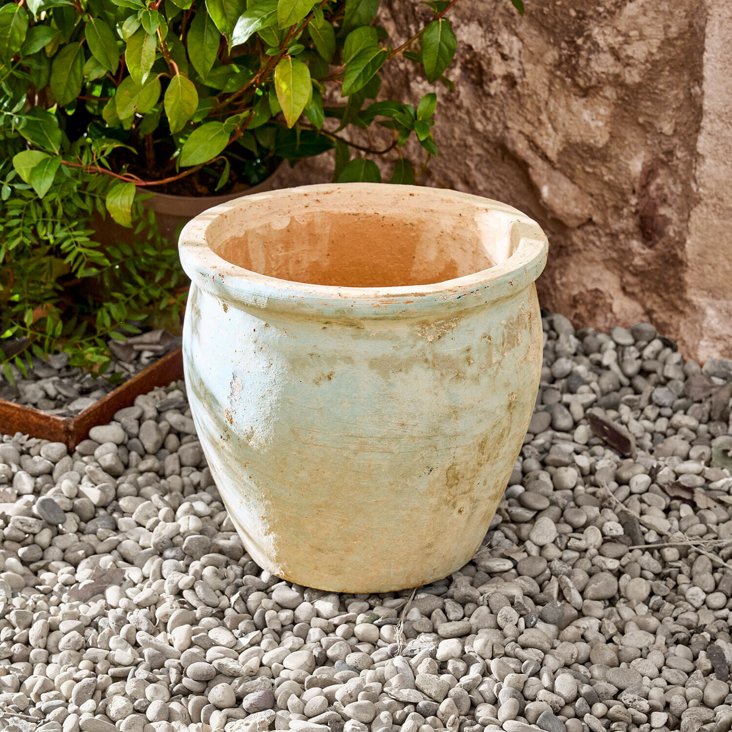 Fioriera Naldorín Grande vaso in ceramica beige chiaro su ciottoli in un giardino esterno