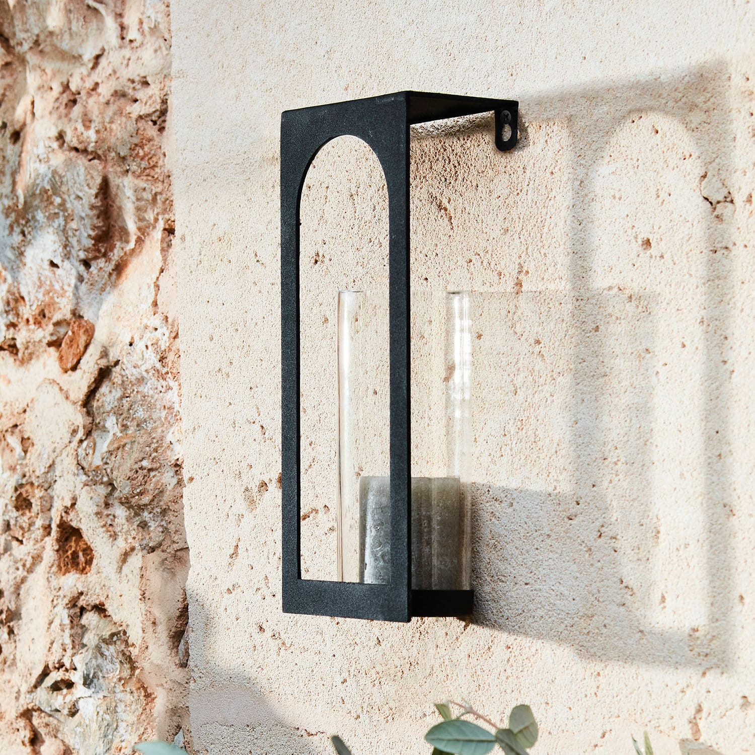 Portacandela da parete Maidis Applique da parete in metallo nero con vetro trasparente e candela su muro di pietra beige
