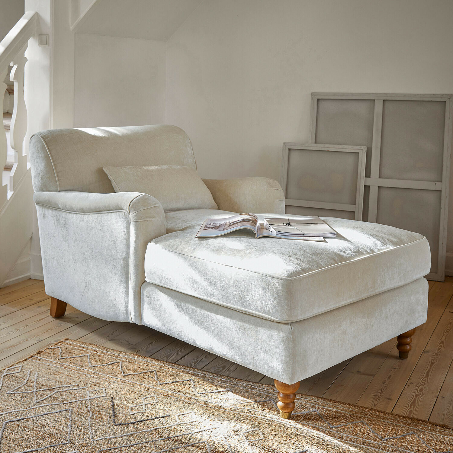 Poltrona beige in tessuto morbido con poggiapiedi e gambe in legno in soggiorno luminoso