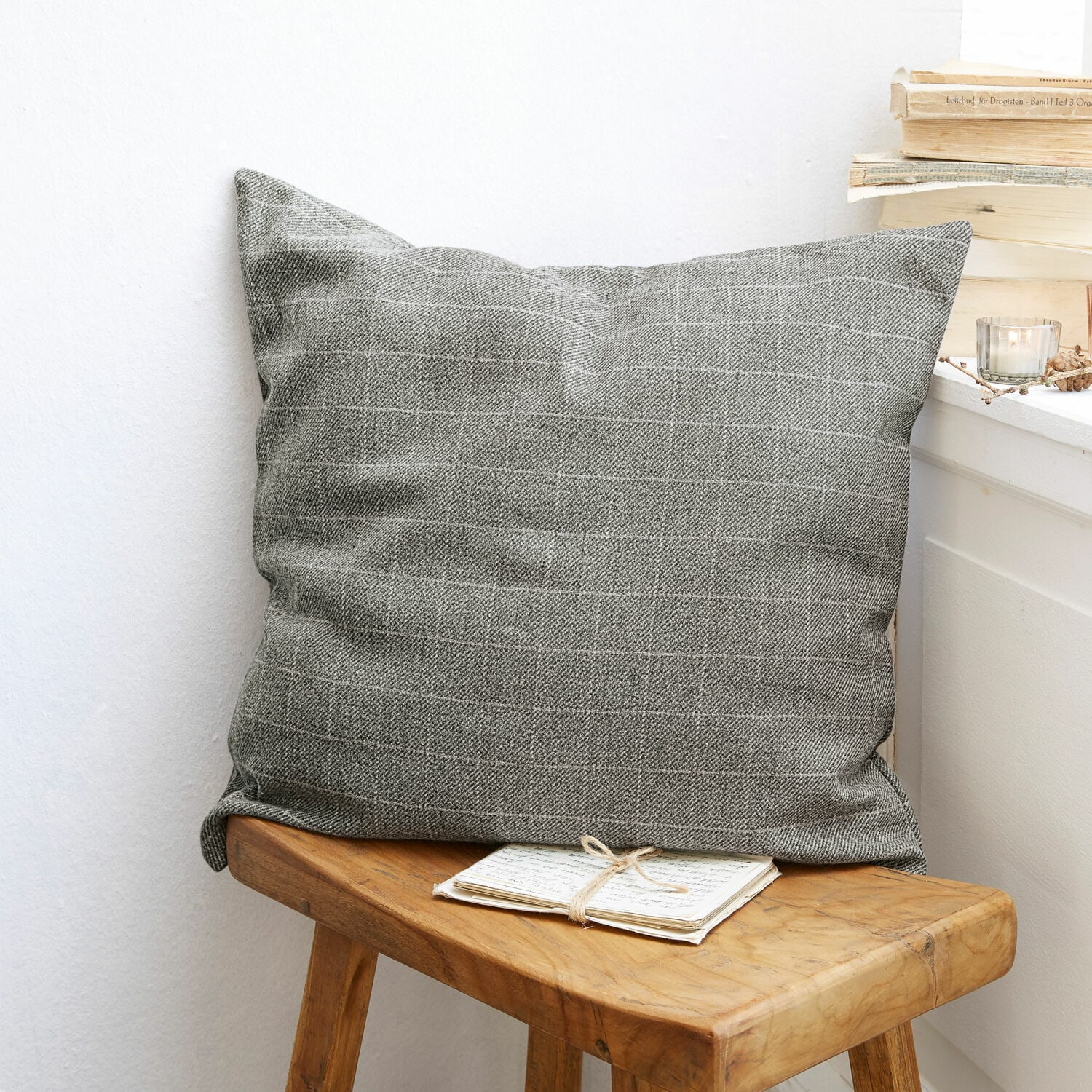 Copricuscino Dublanc Cuscino decorativo grigio con motivo a quadri su sgabello in legno in ambiente accogliente
