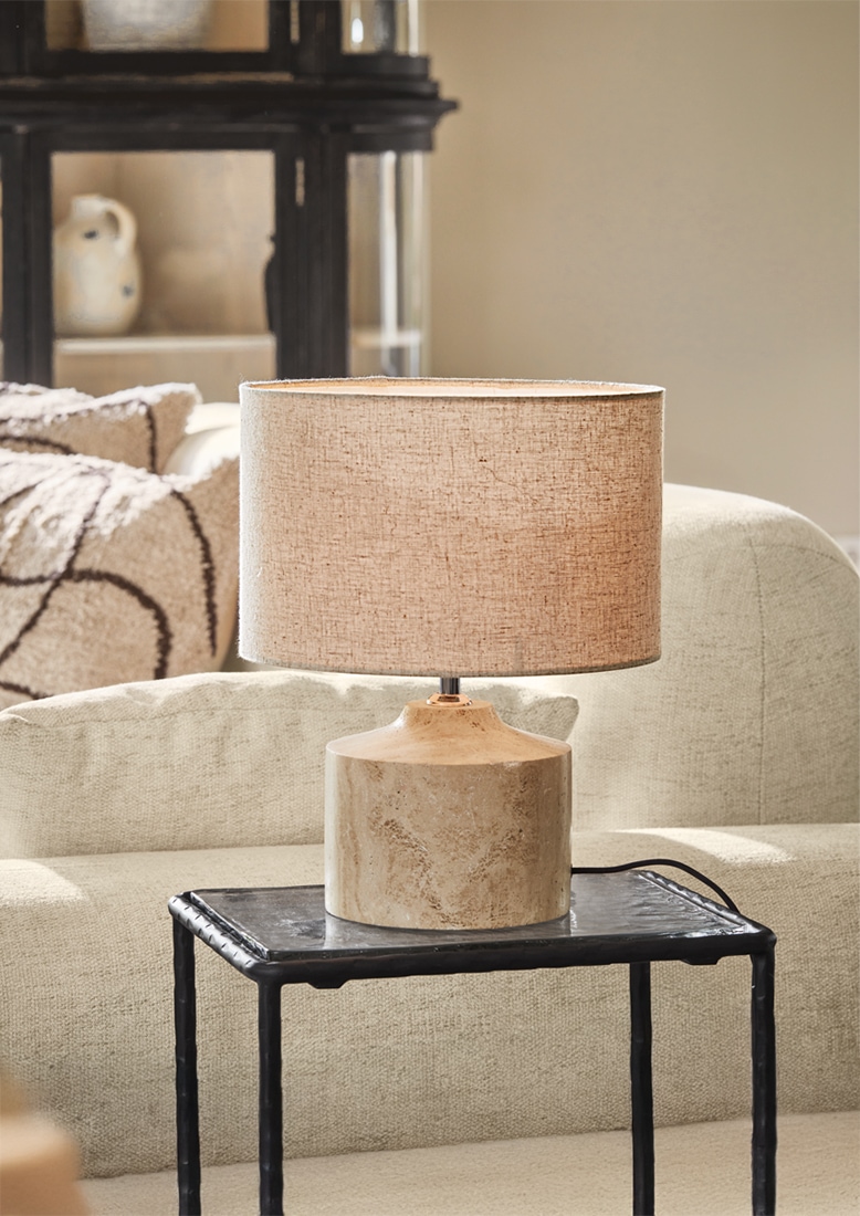 Lampada da tavolo con paralume beige e base in ceramica color sabbia su tavolino nero