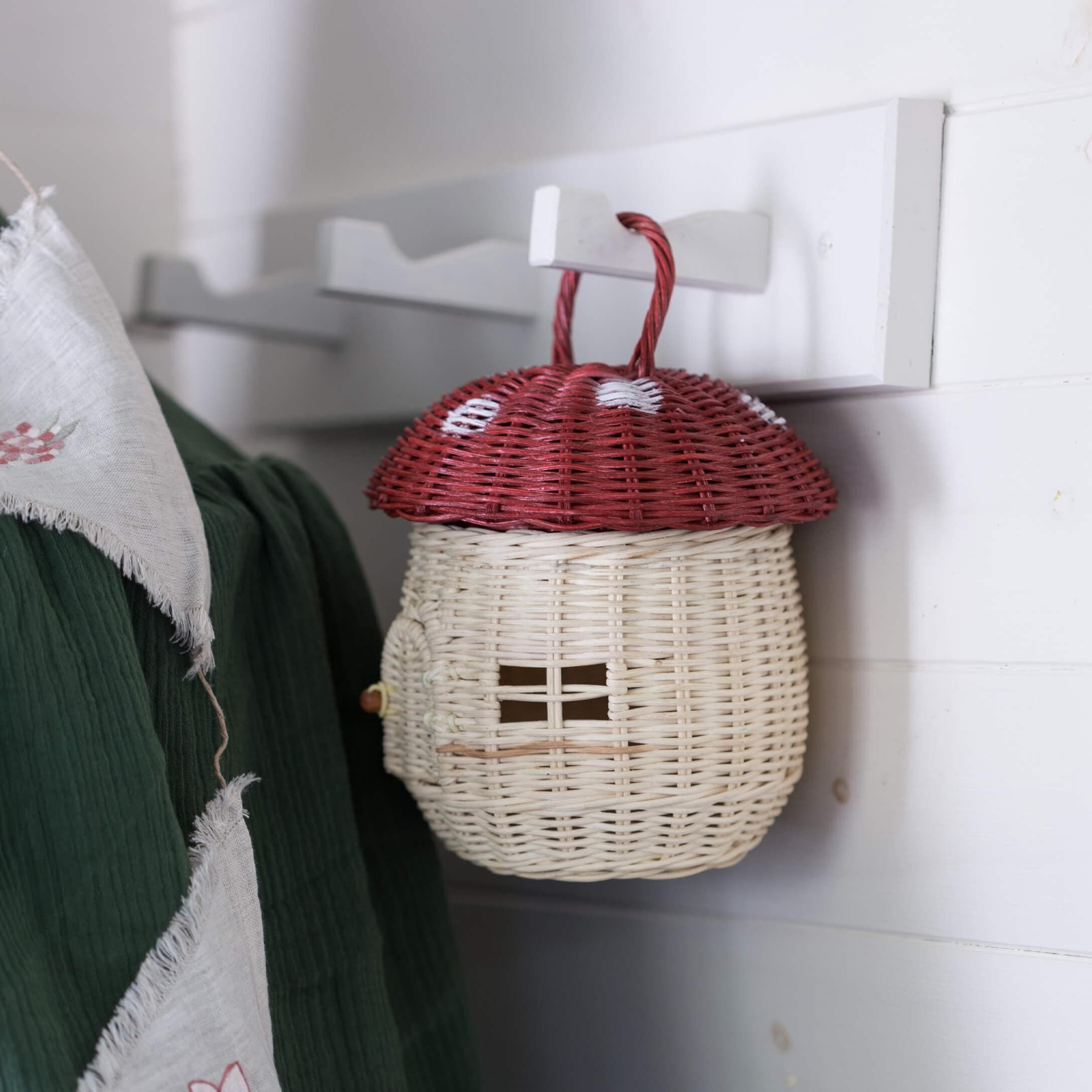 Cesto decorativo in vimini a forma di fungo con cappello rosso e corpo bianco appeso a un gancio