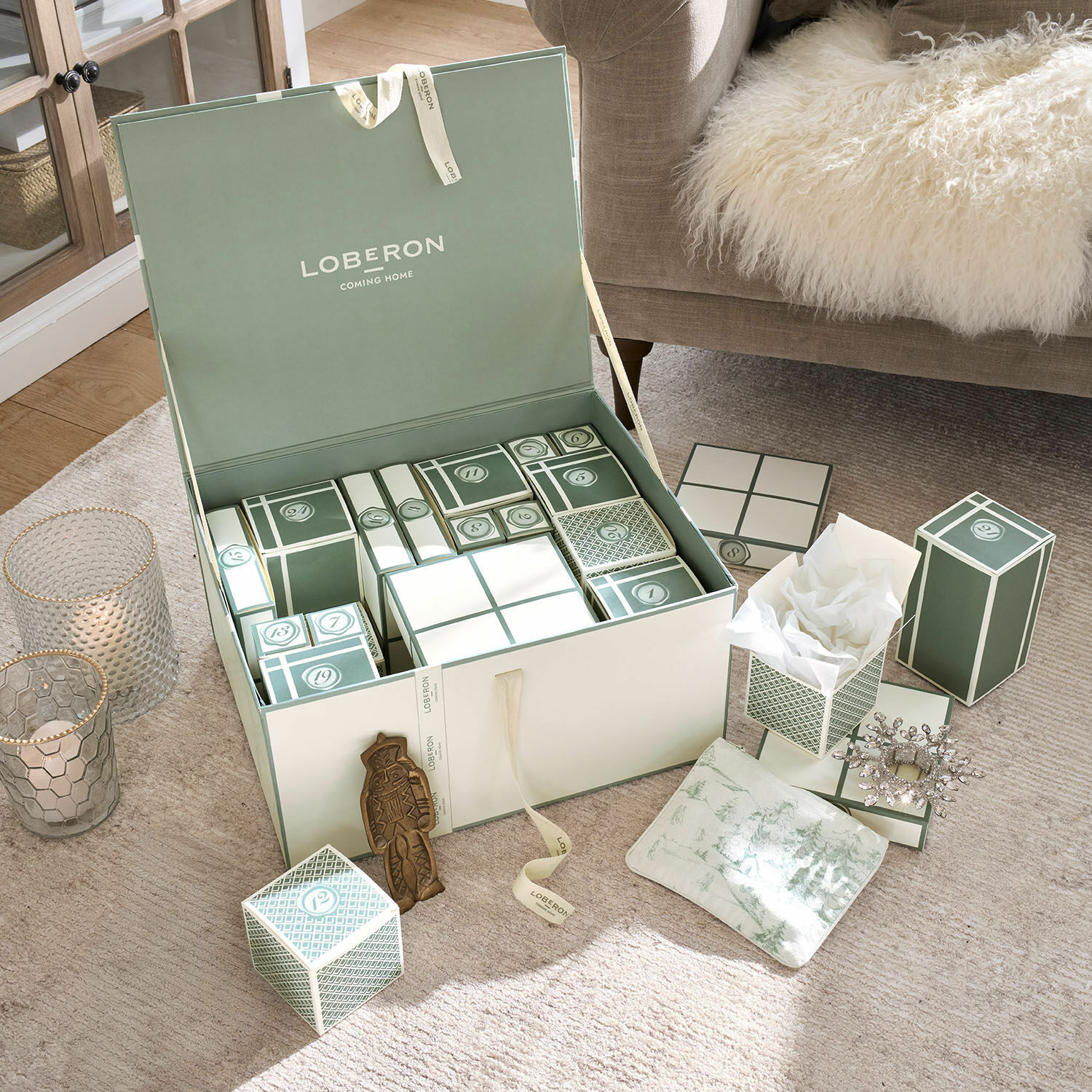 Calendario dell'Avvento Calavira Set di scatole verdi e bianche calendario dell'Avvento su tappeto beige accanto a divano con coperta di pelliccia
