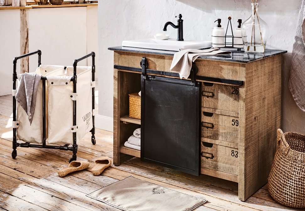 Bagno industriale con mobile in legno, cassetti in metallo nero e lavabo bianco su piano in pietra