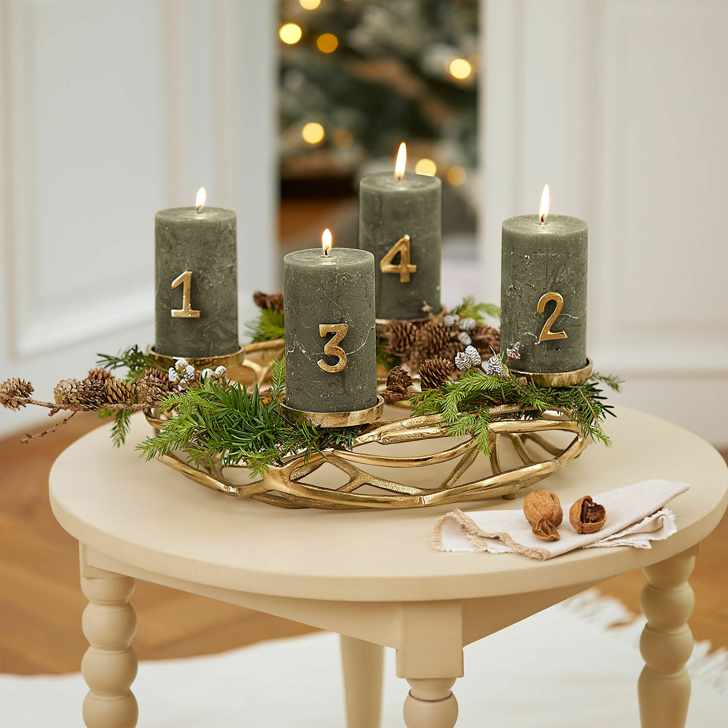 Ghirlanda portacandele Coldfield Corona d'Avvento verde con quattro candele numerate in oro su tavolo beige