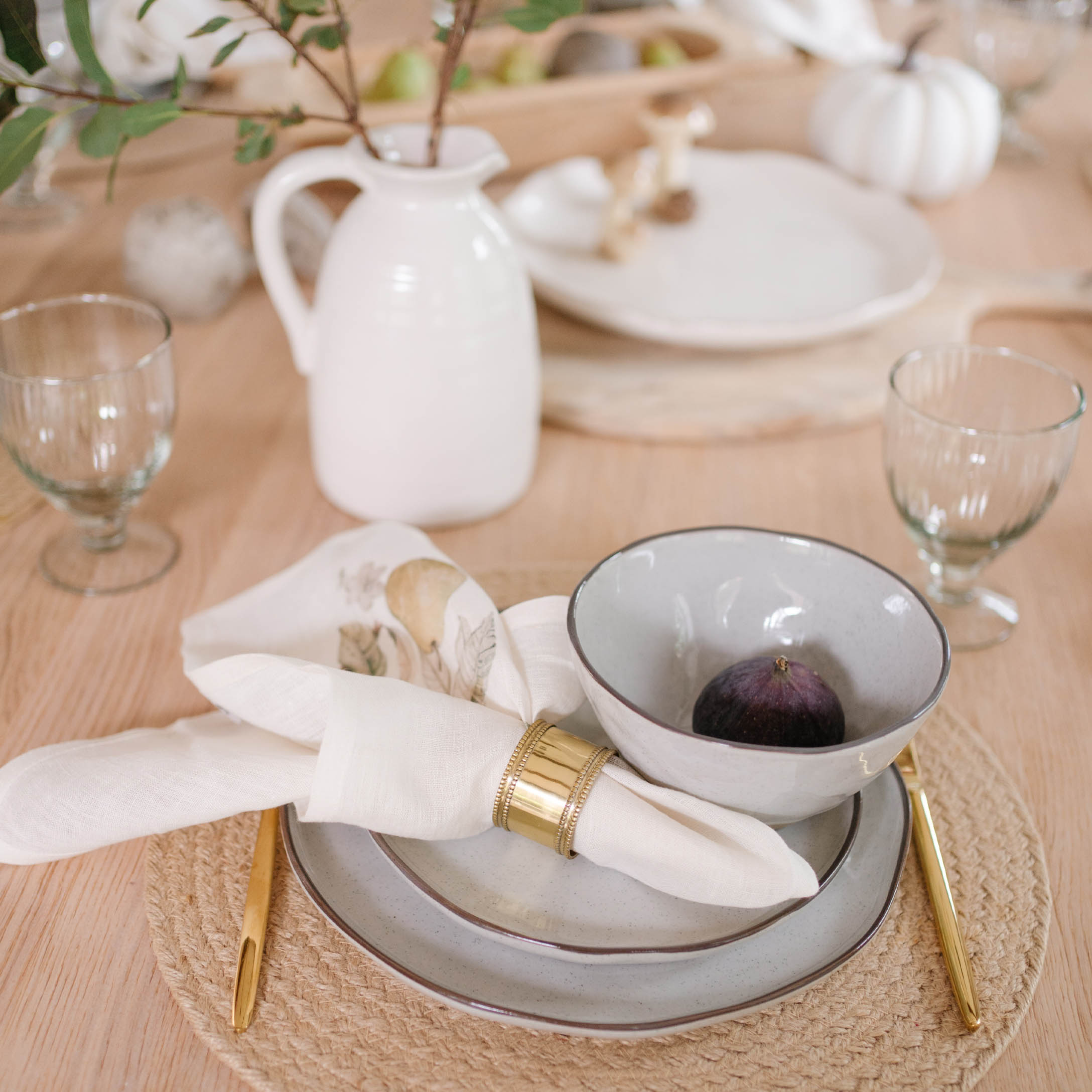 Servizio da tavola in ceramica grigio chiaro con posate dorate e tovagliolo di lino su base naturale