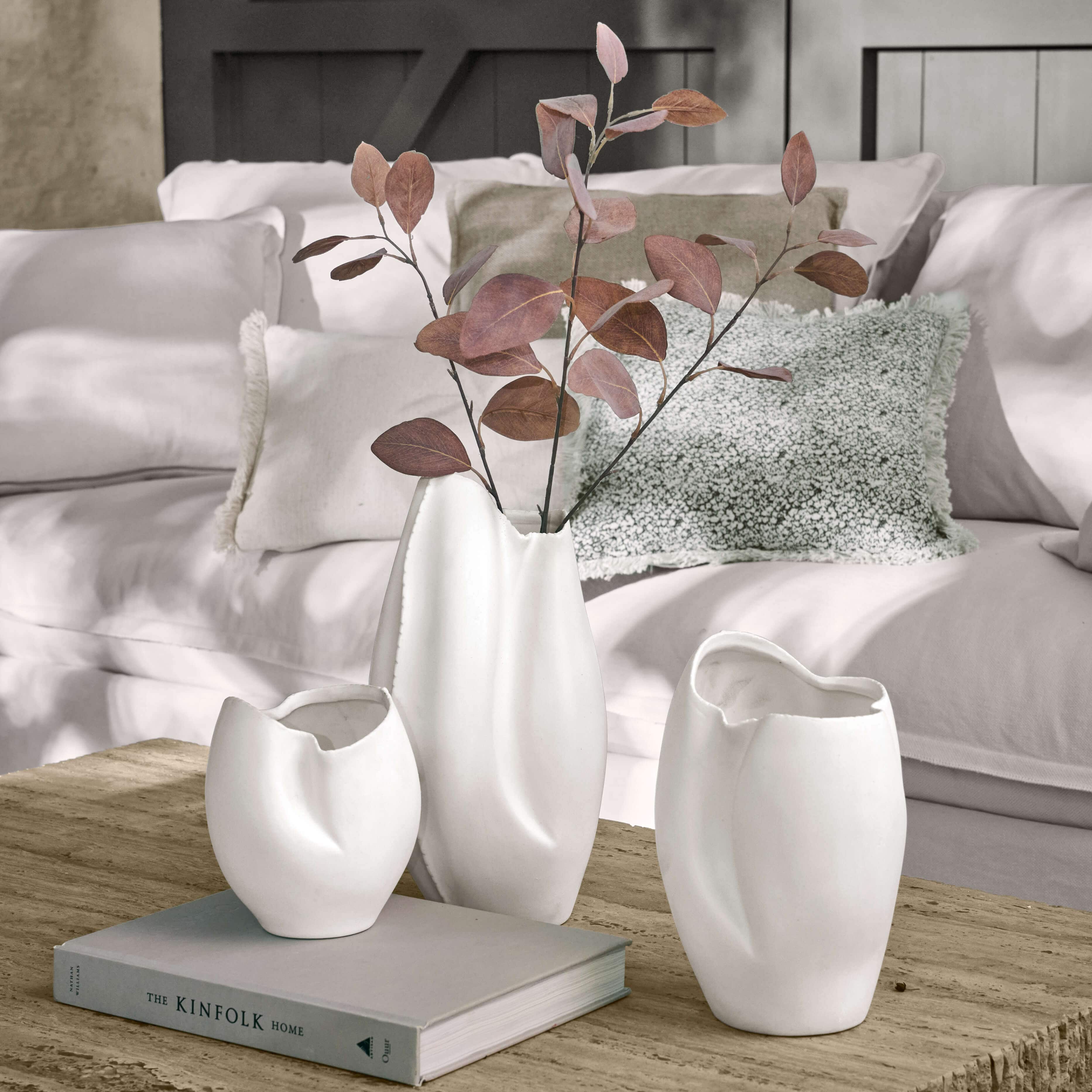 Set di tre vasi in ceramica bianca con forma irregolare su tavolo in legno in soggiorno