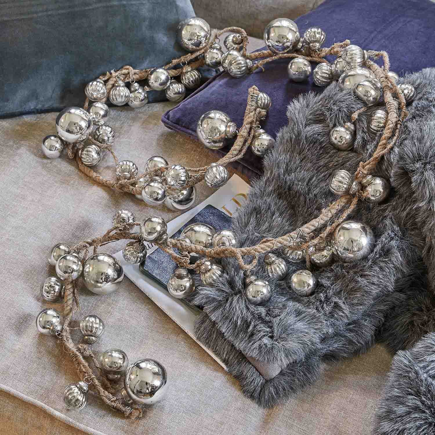 Catena decorativa con palline metalliche argento su corda di juta su cuscini morbidi e pelliccia sintetica