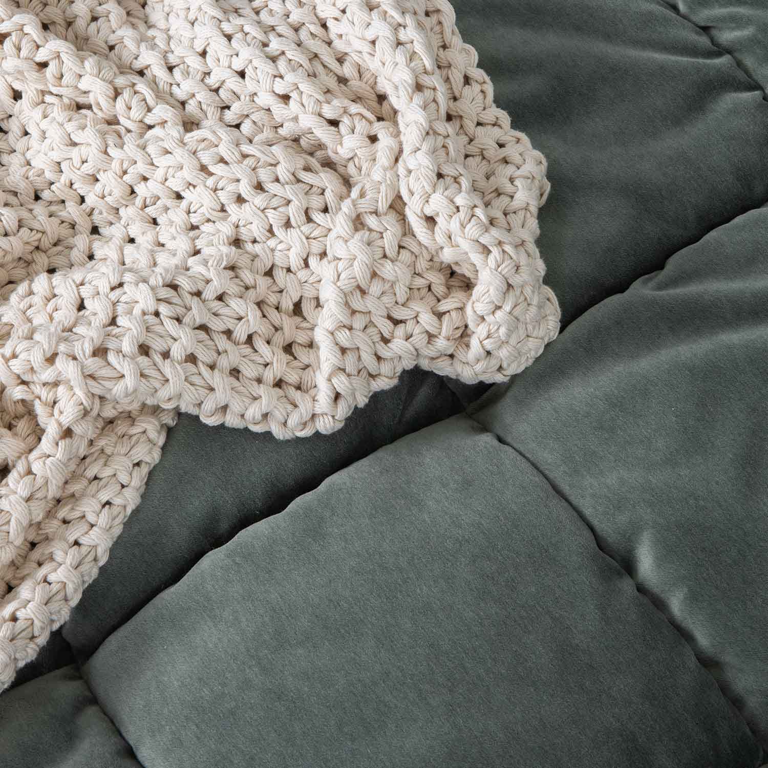 Coperta spessa in cotone crema lavorata a mano su materasso verde morbido per relax