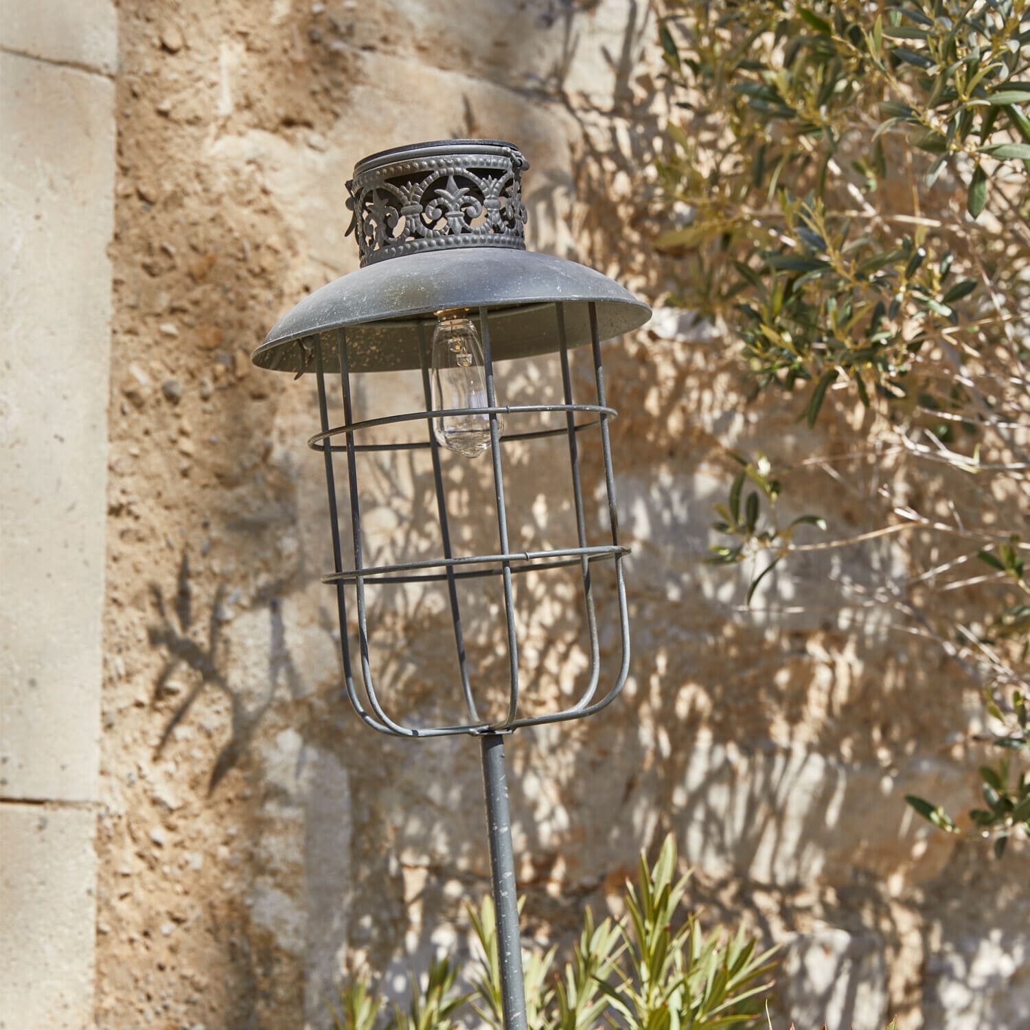 Lanterna solare Nistos Lampada da giardino in metallo nero stile vintage con paralume decorativo e lampadina visibile su muro in pietra