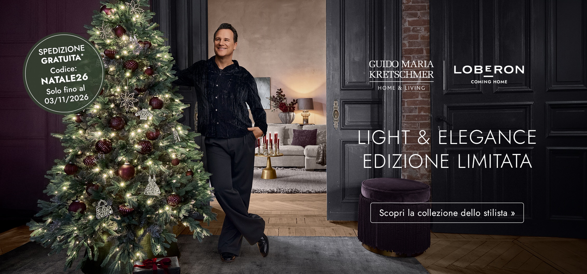 Uomo accanto all'albero di Natale illuminato con decorazioni bordeaux in un ambiente elegante