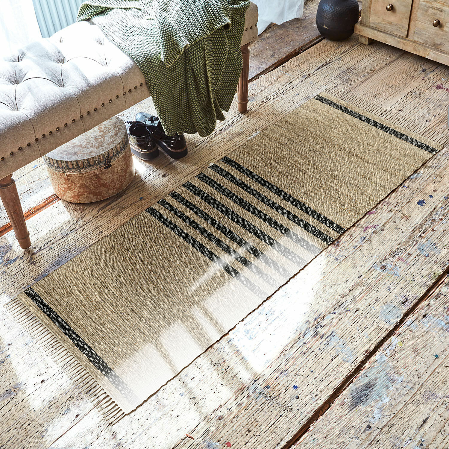 Passatoia Orgeval Tappeto beige con strisce nere in materiale naturale su pavimento in legno in soggiorno