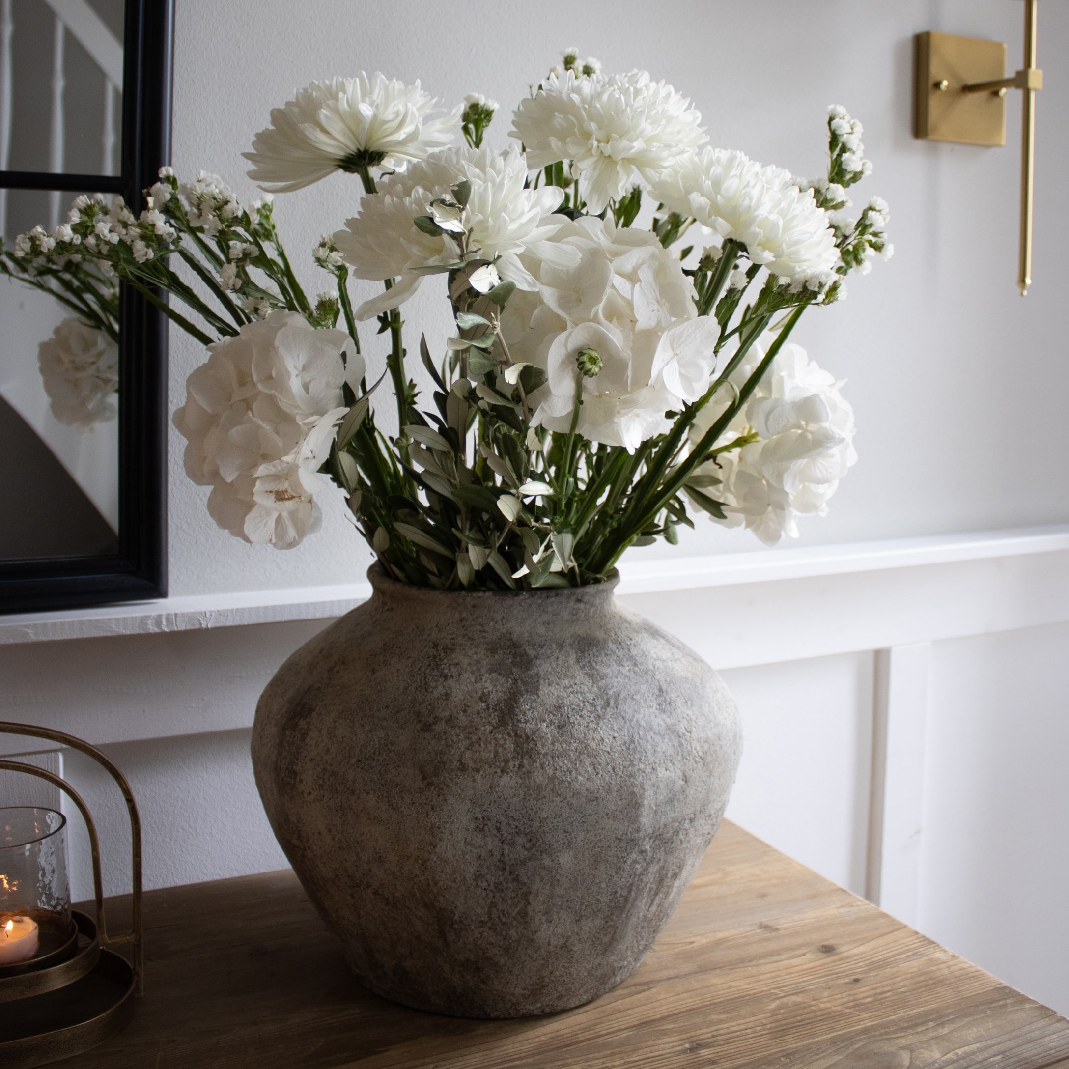 Grande vaso in ceramica grigia con fiori bianchi su tavolo in legno in interno moderno