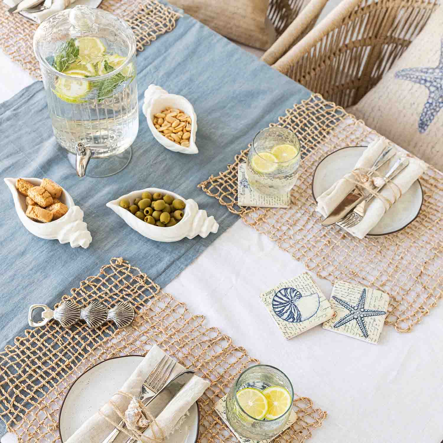 Tavola estiva con decorazioni marine, ciotole bianche in ceramica a forma di conchiglia con snack e limonata