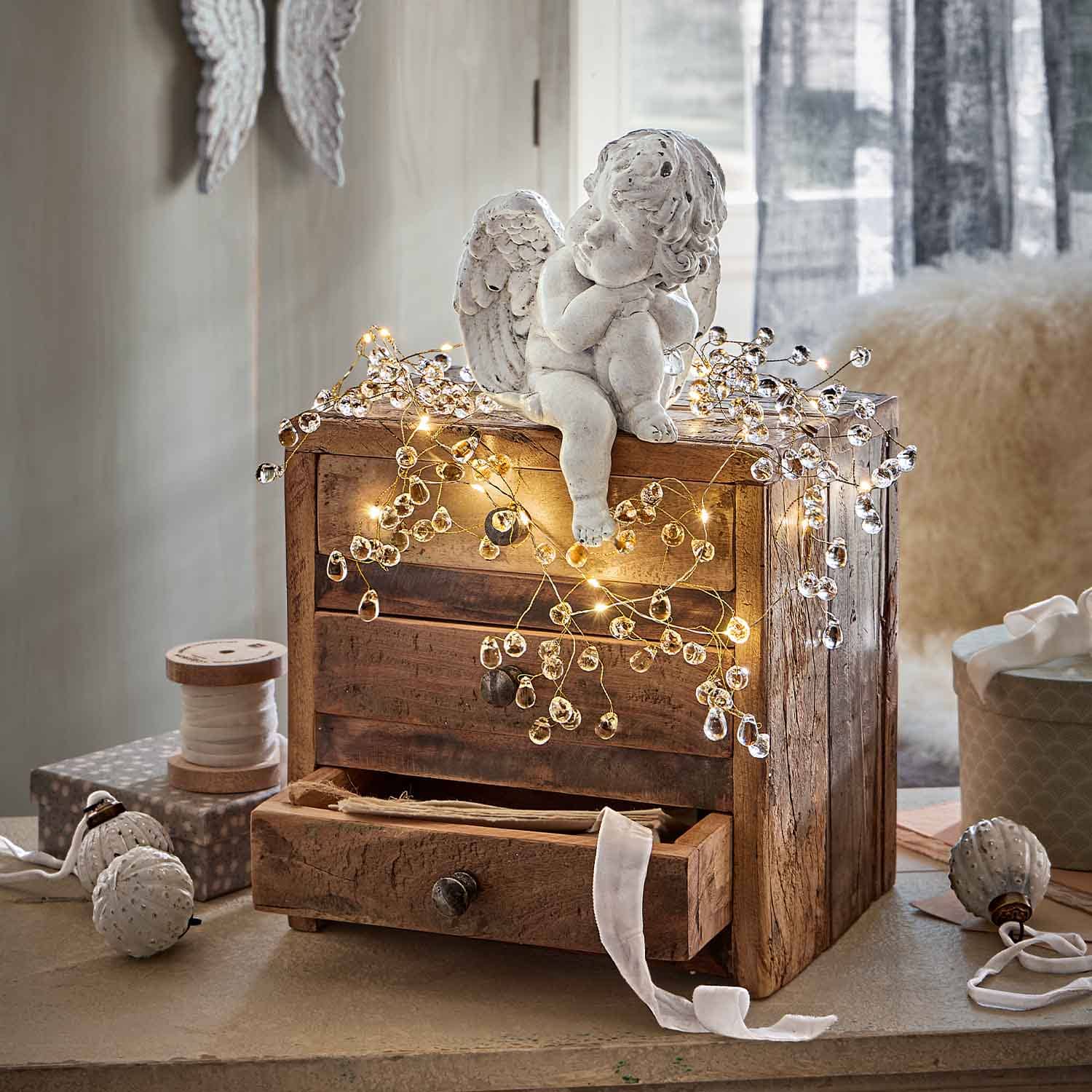 Statua di angelo in ceramica bianca su cassettiera in legno decorata con luci LED calde