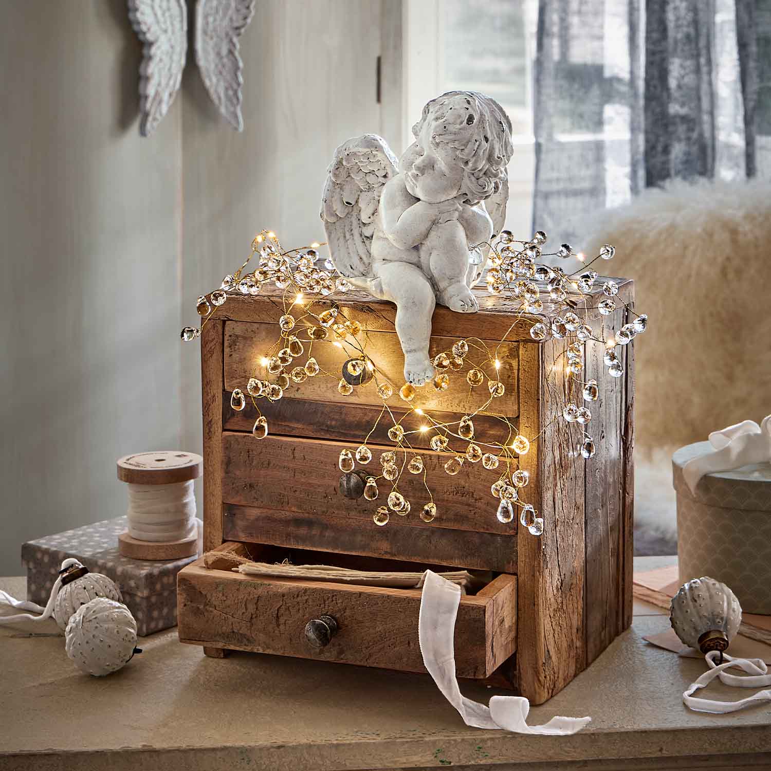 Statua di angelo in ceramica bianca su cassettiera in legno decorata con luci LED calde