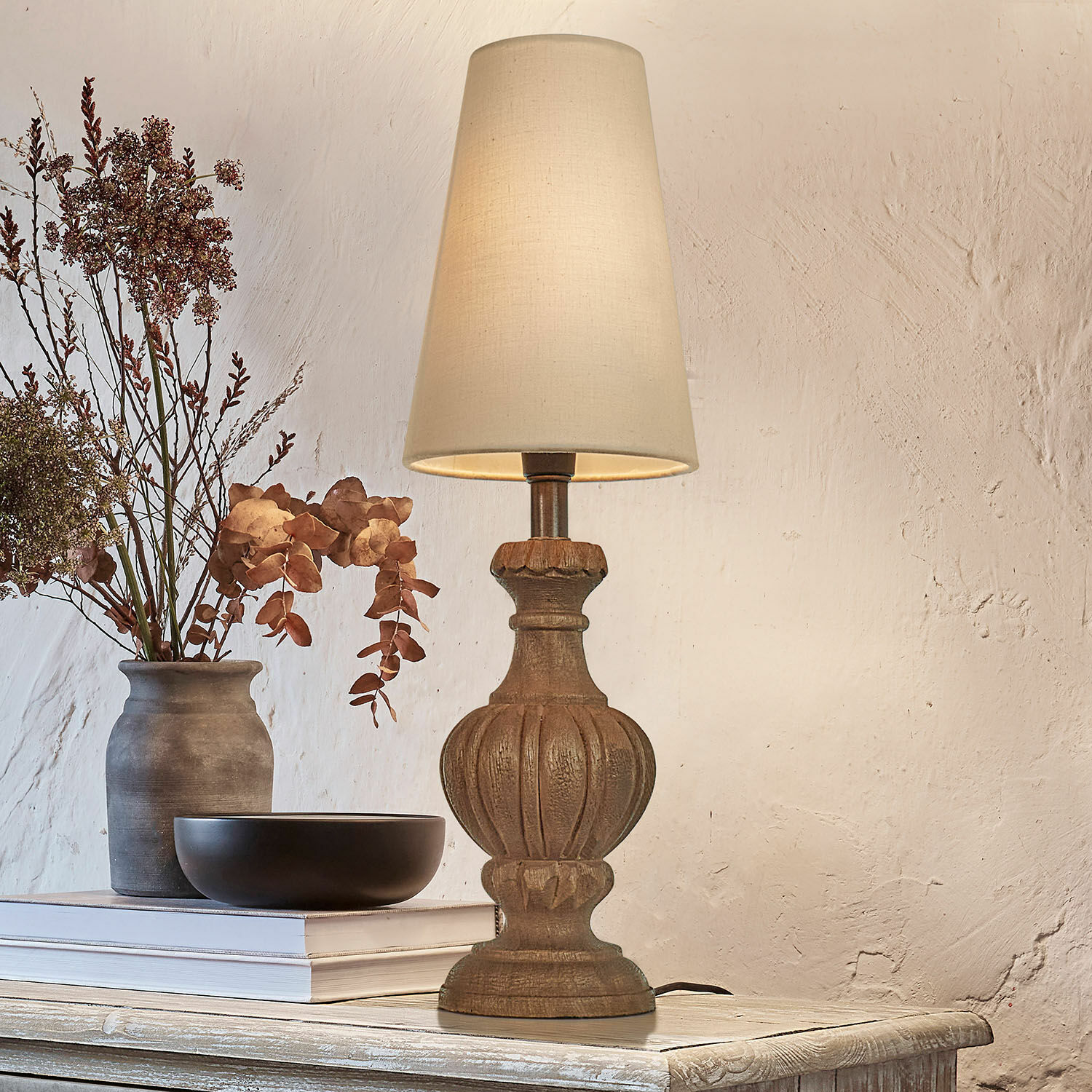 Lampada da tavolo Airoux Lampada da tavolo con base in legno intagliato e paralume crema su tavolo rustico decorato