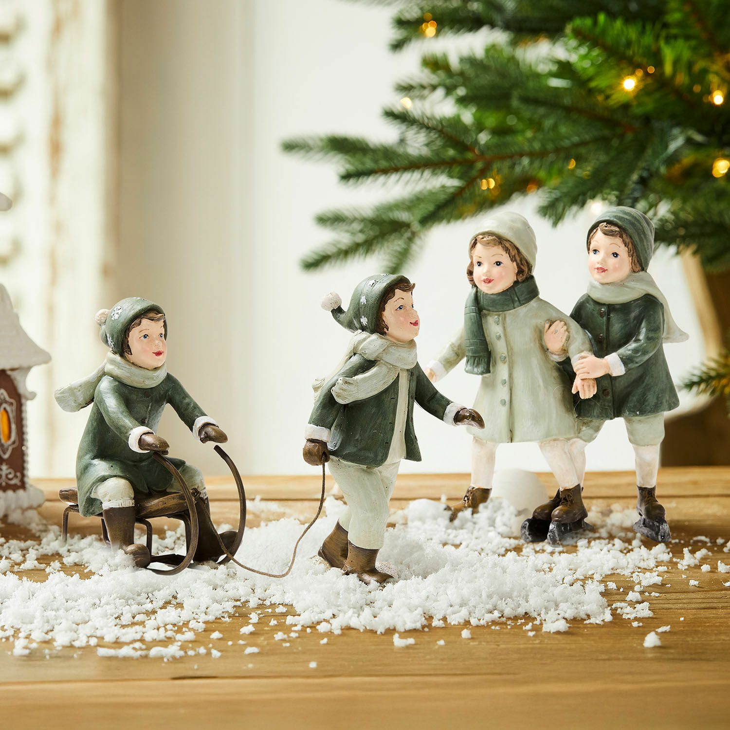 Coppia di statuine Andros Figure di bambini che giocano nella neve con slitta e pattini, decorazione invernale su tavolo di legno