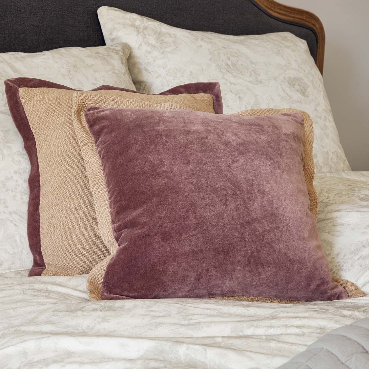 Set di cuscini decorativi in velluto e lino rosa e beige su letto con motivo floreale