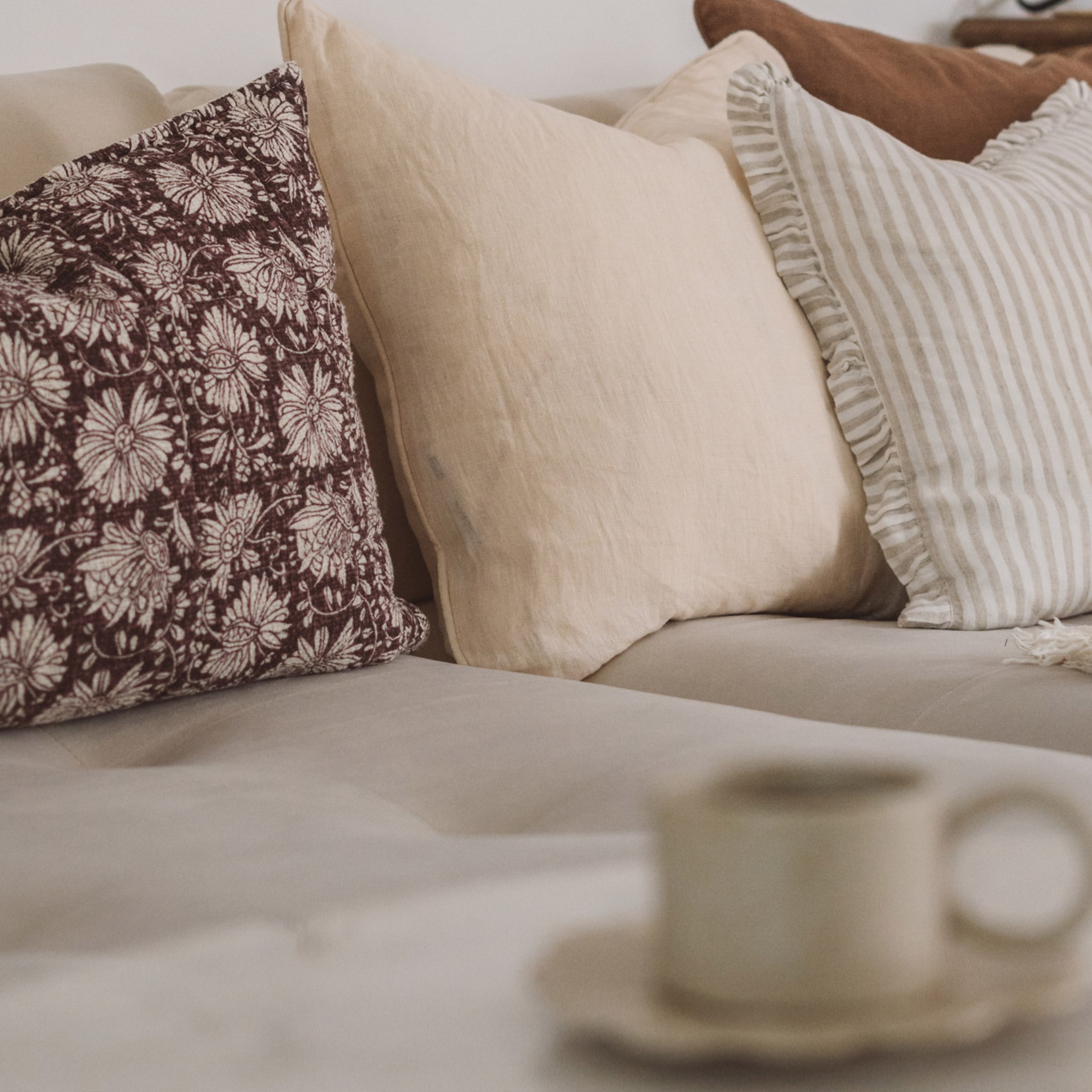 Set di cuscini decorativi beige e marroni su divano chiaro in soggiorno accogliente