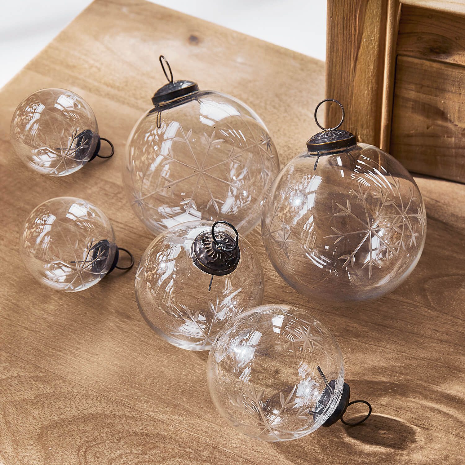 Palline di Natale in vetro trasparente con motivo fiocco di neve inciso su tavolo in legno, decorazione festiva