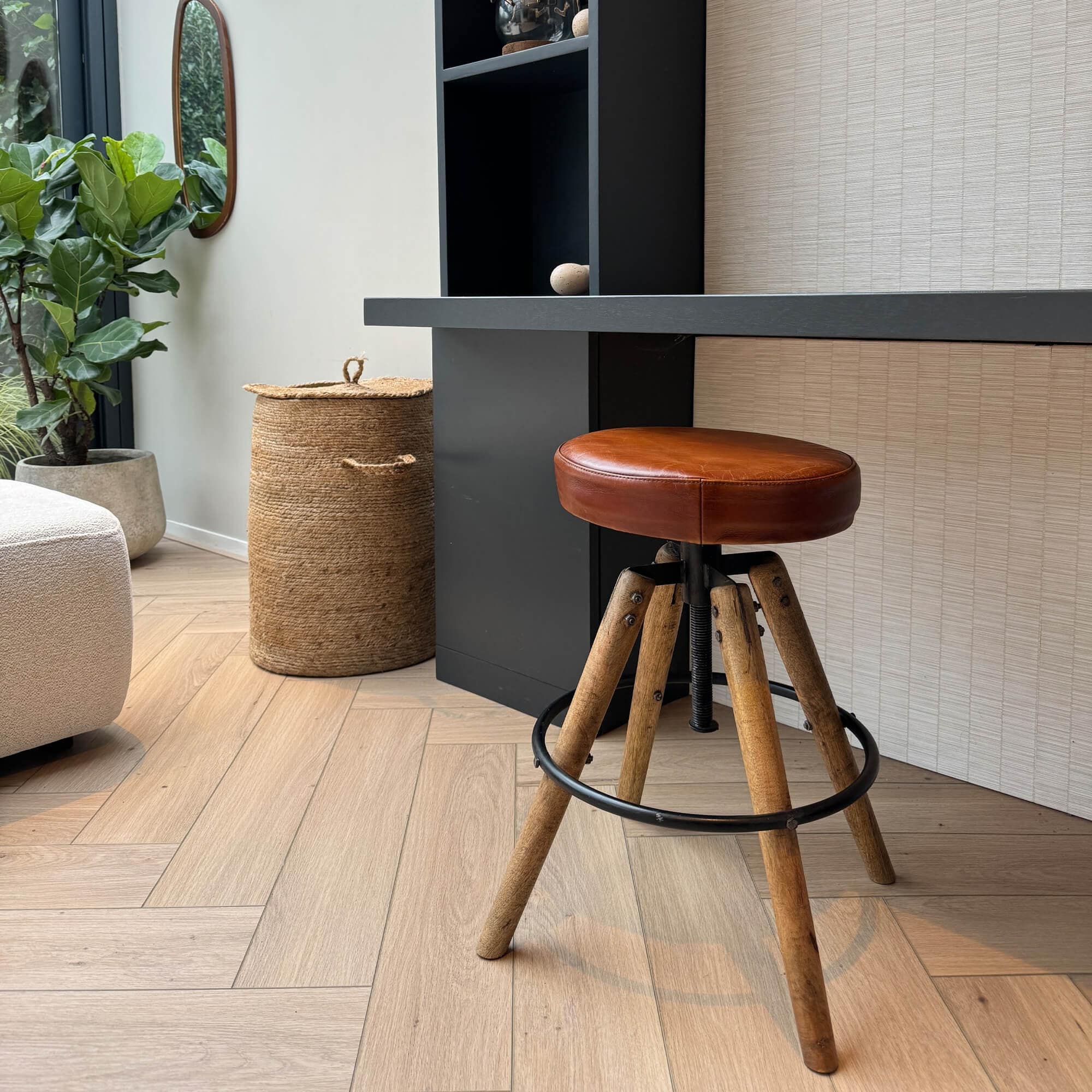 Sgabello da bar con seduta in pelle marrone e gambe in legno su pavimento chiaro