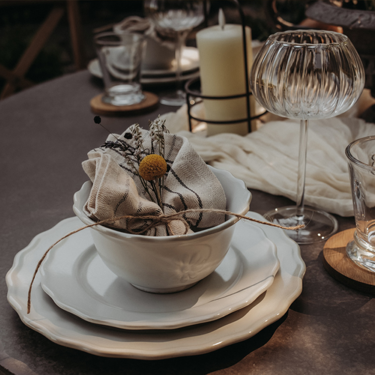 Set di stoviglie in ceramica bianca con ciotola, piatti e tovagliolo di lino decorato con fiori su tavolo