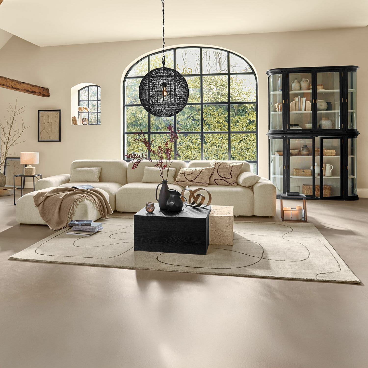 Tappeto Lavinois Ampio soggiorno con divano beige in tessuto e tavolino nero in legno su tappeto decorato