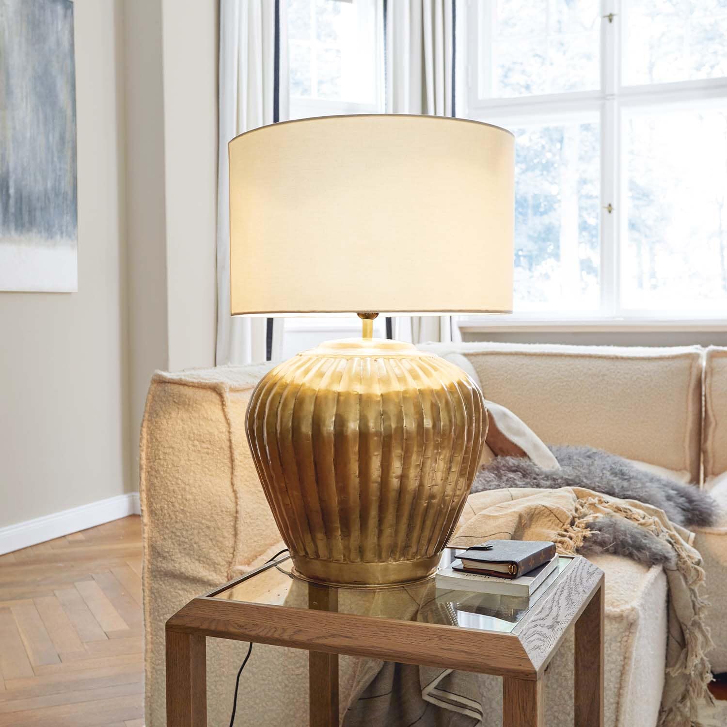 Lampada da tavolo in ottone con paralume beige su tavolo in legno in soggiorno luminoso