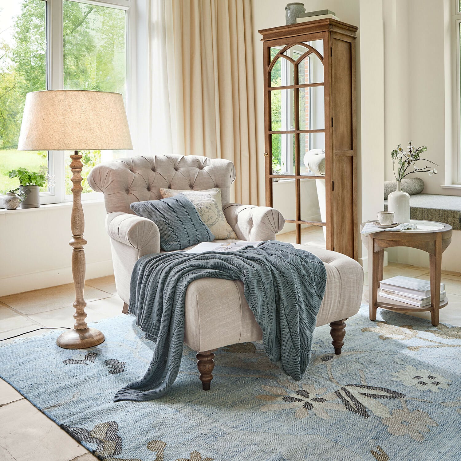 Chaise longue Springfield Village Poltrona beige in tessuto con schienale capitonné e coperta blu su tappeto blu in soggiorno luminoso