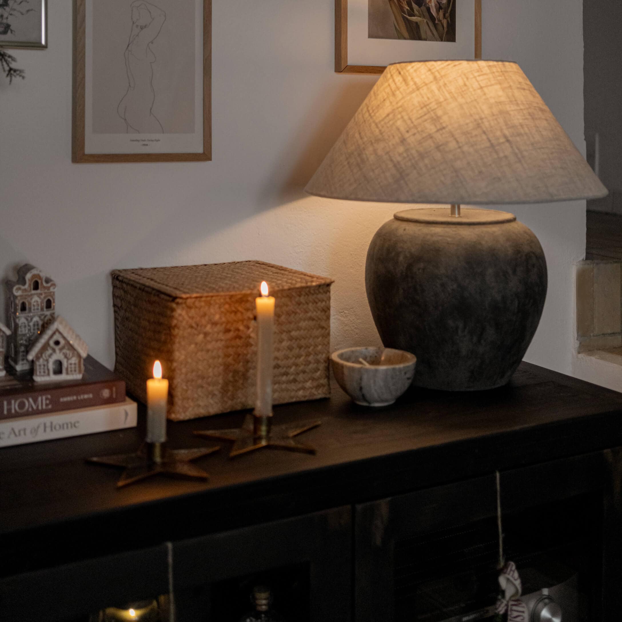 Lampada da tavolo in ceramica grigio scuro con paralume beige su mobile scuro con candele e decorazioni