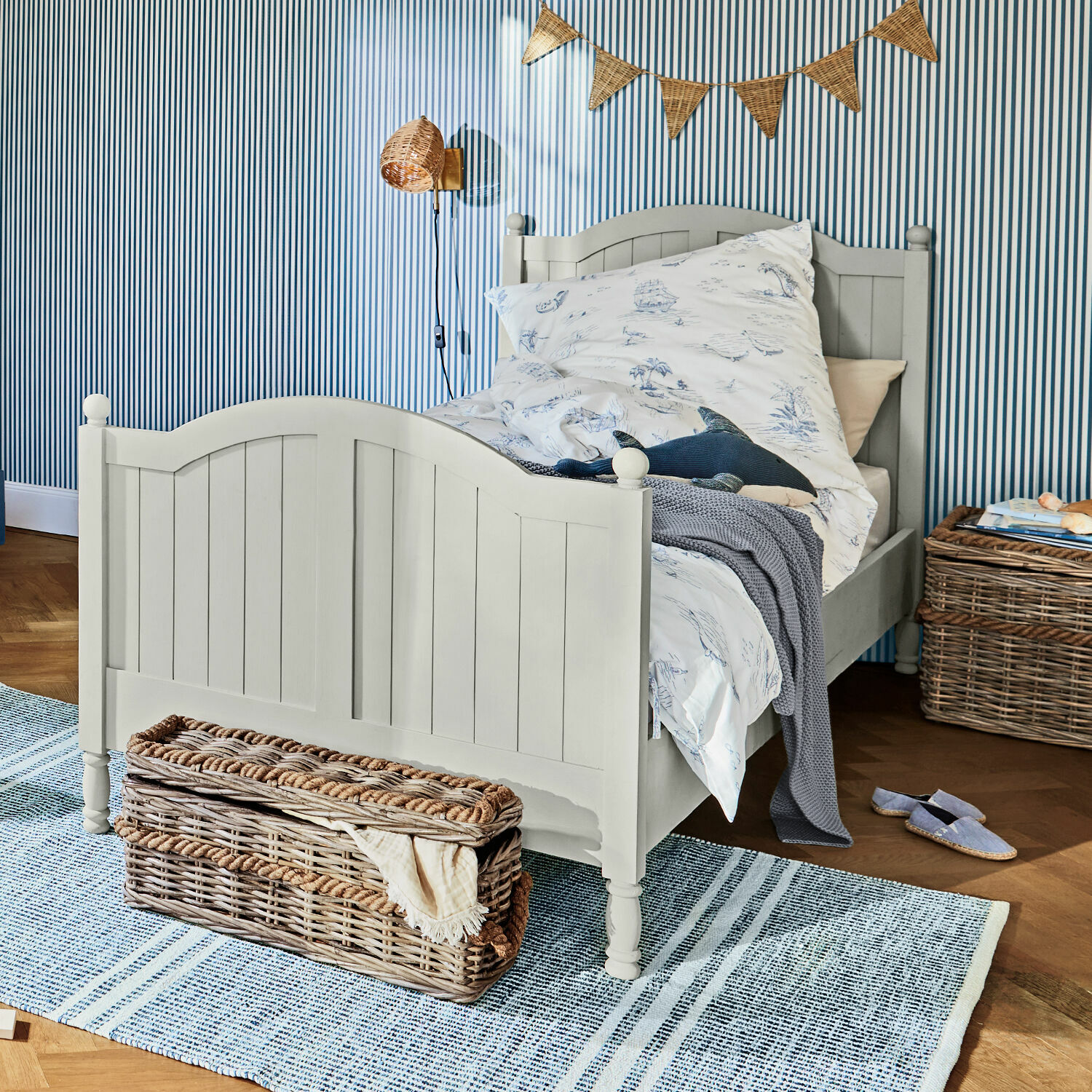 Letto Alarion Letto per bambini in legno grigio con biancheria da letto a tema marino e cesto in vimini su tappeto