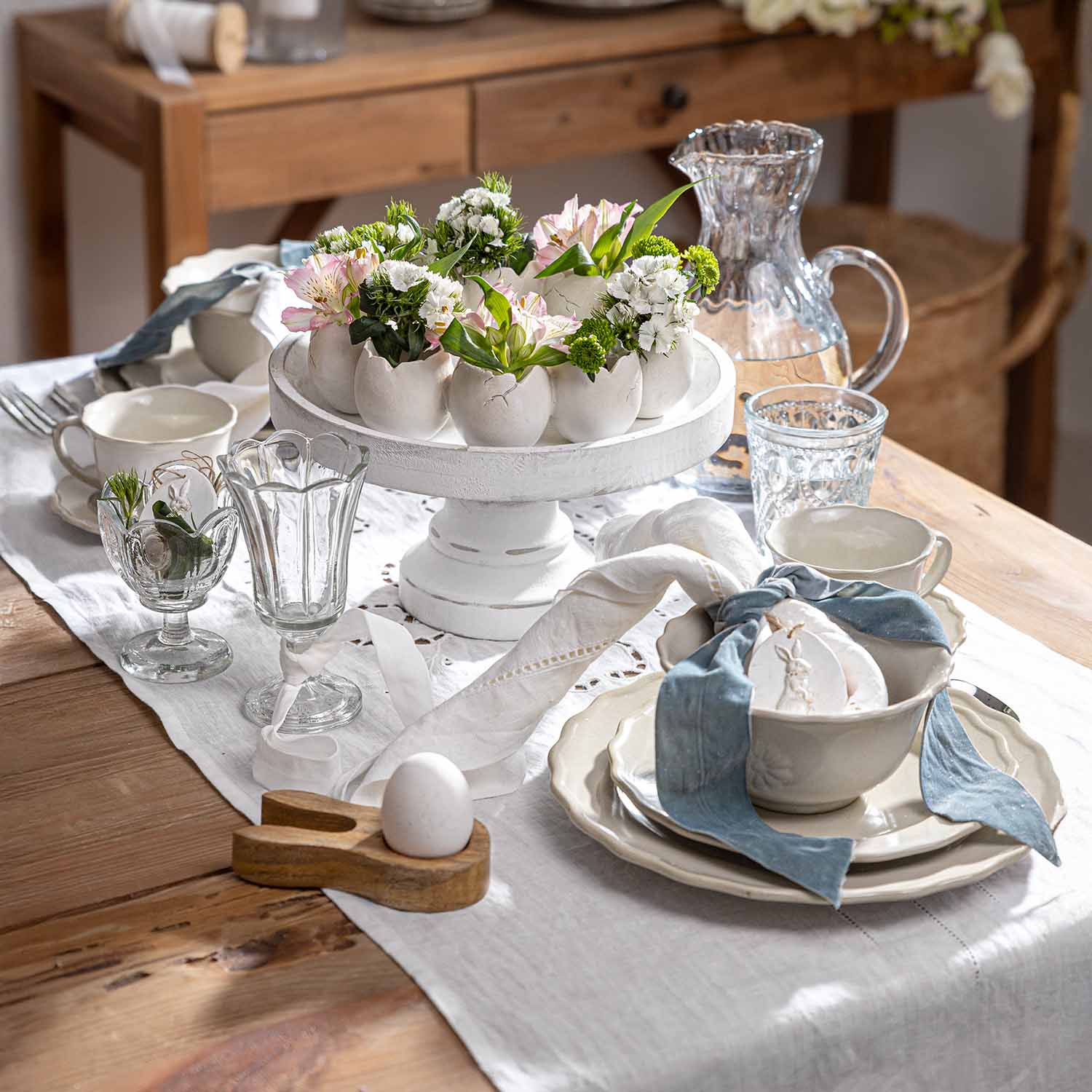 Portaoggetti in ceramica bianca con vasi a forma di uovo e fiori su tavolo rustico in legno