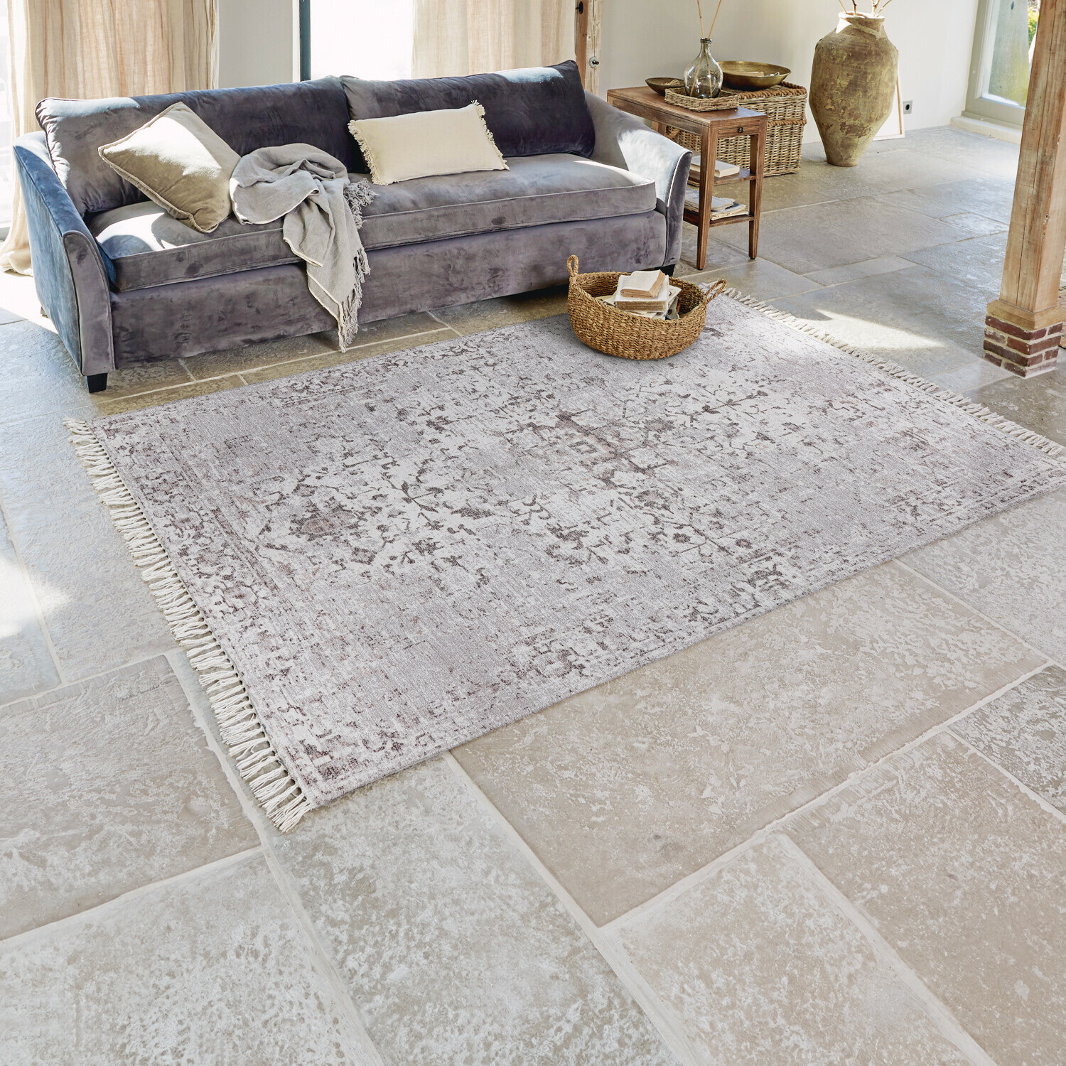 Tappeto Delpheer Tappeto grigio con motivo delicato e frange su pavimento in pietra in soggiorno luminoso con divano grigio