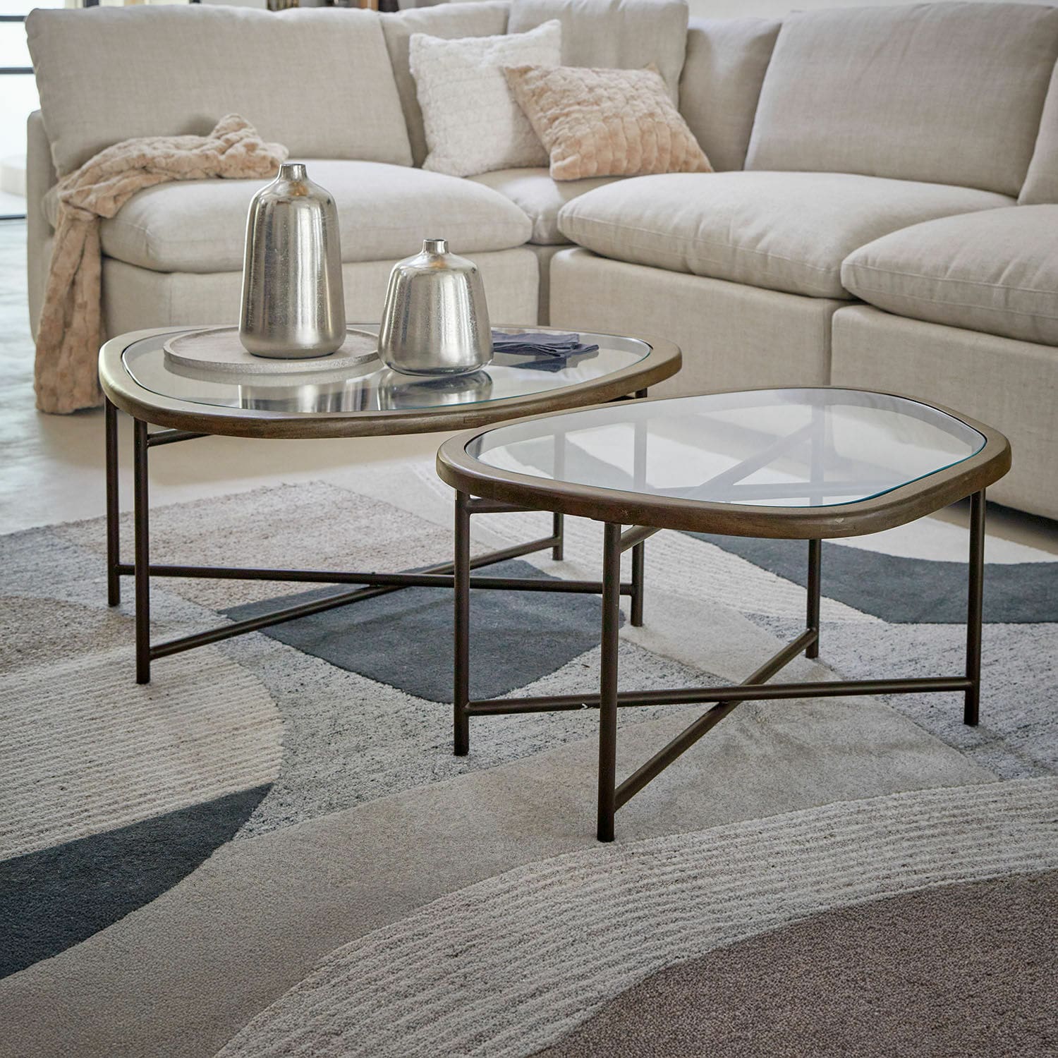 Coppia di tavolini da salotto Kembria Set di due tavolini con struttura in metallo e piano in vetro in soggiorno con divano beige