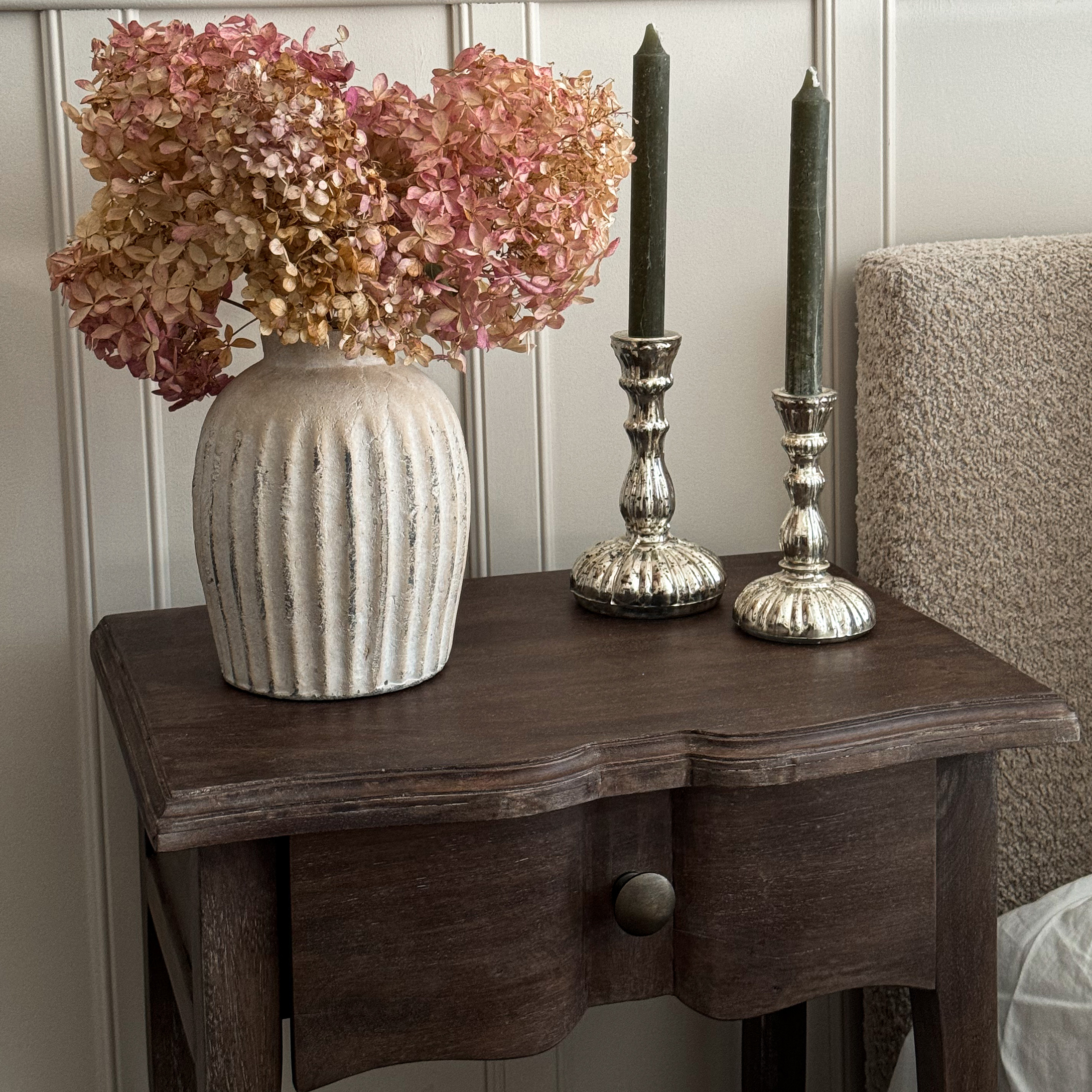 Vaso in ceramica beige con fiori secchi rosa su tavolo in legno scuro per decorazione