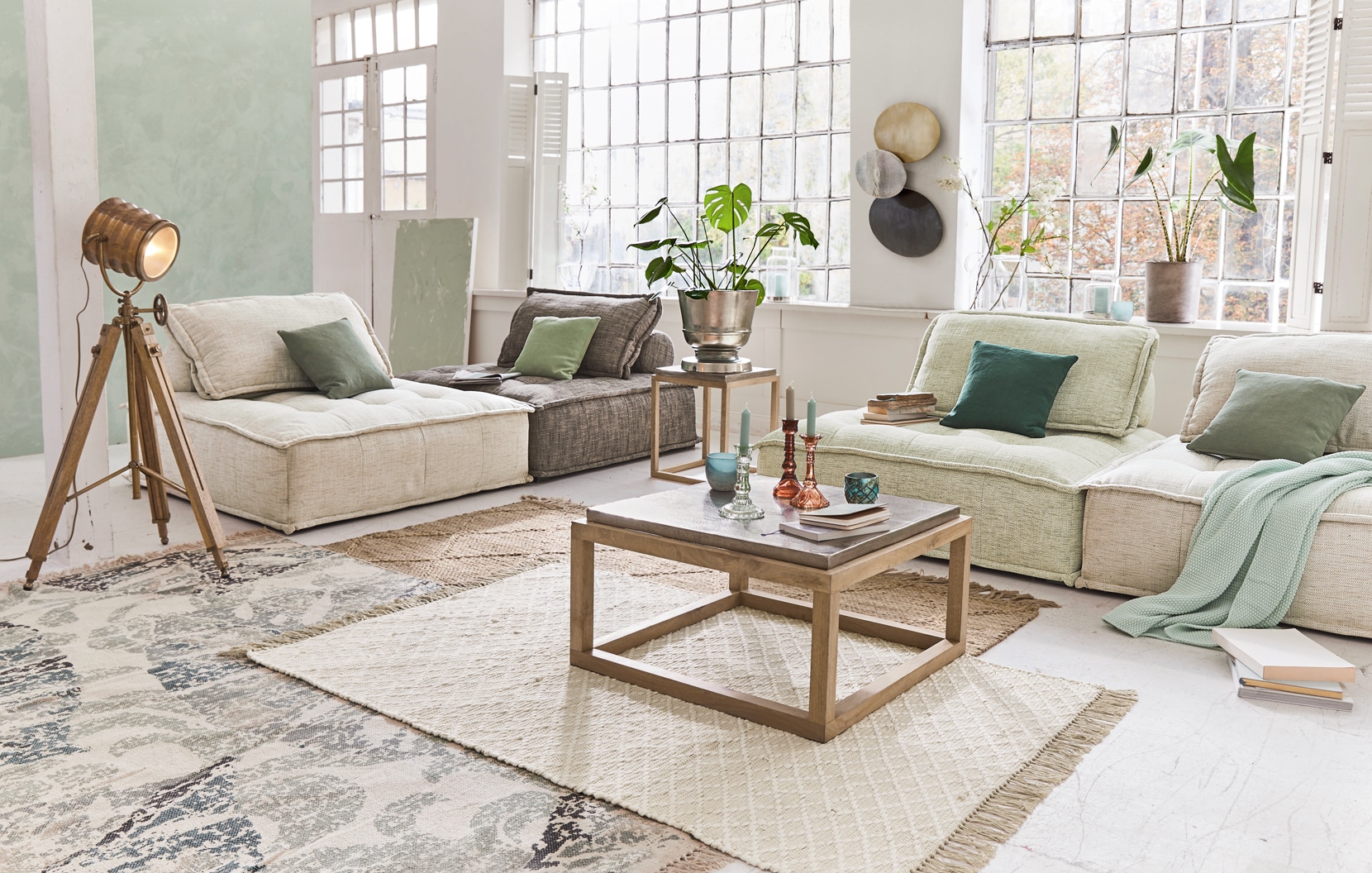 Soggiorno accogliente con divani beige e grigi, tavolino in legno e lampada stile loft