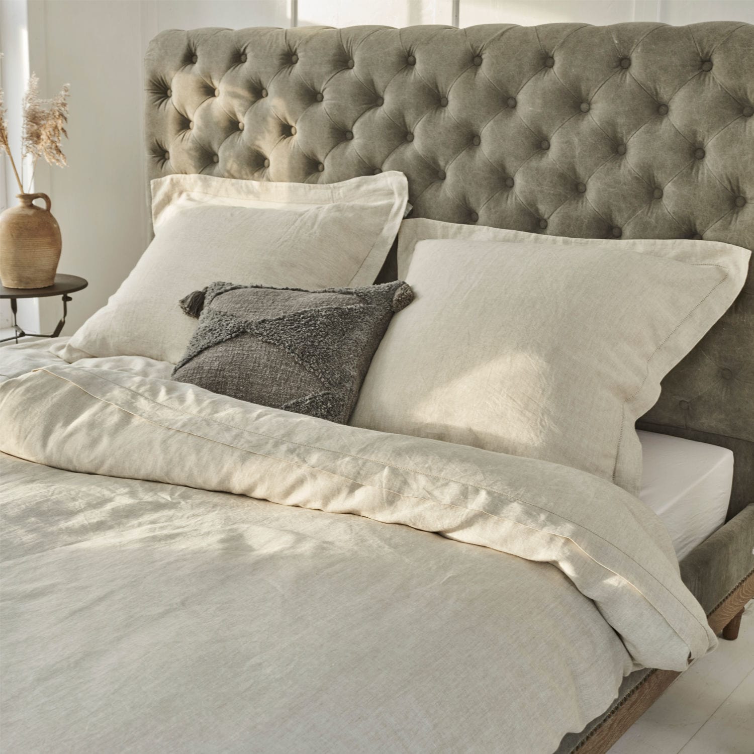Biancheria da letto Kilanema Biancheria da letto beige in lino su letto con testiera trapuntata grigia, cuscino decorativo grigio