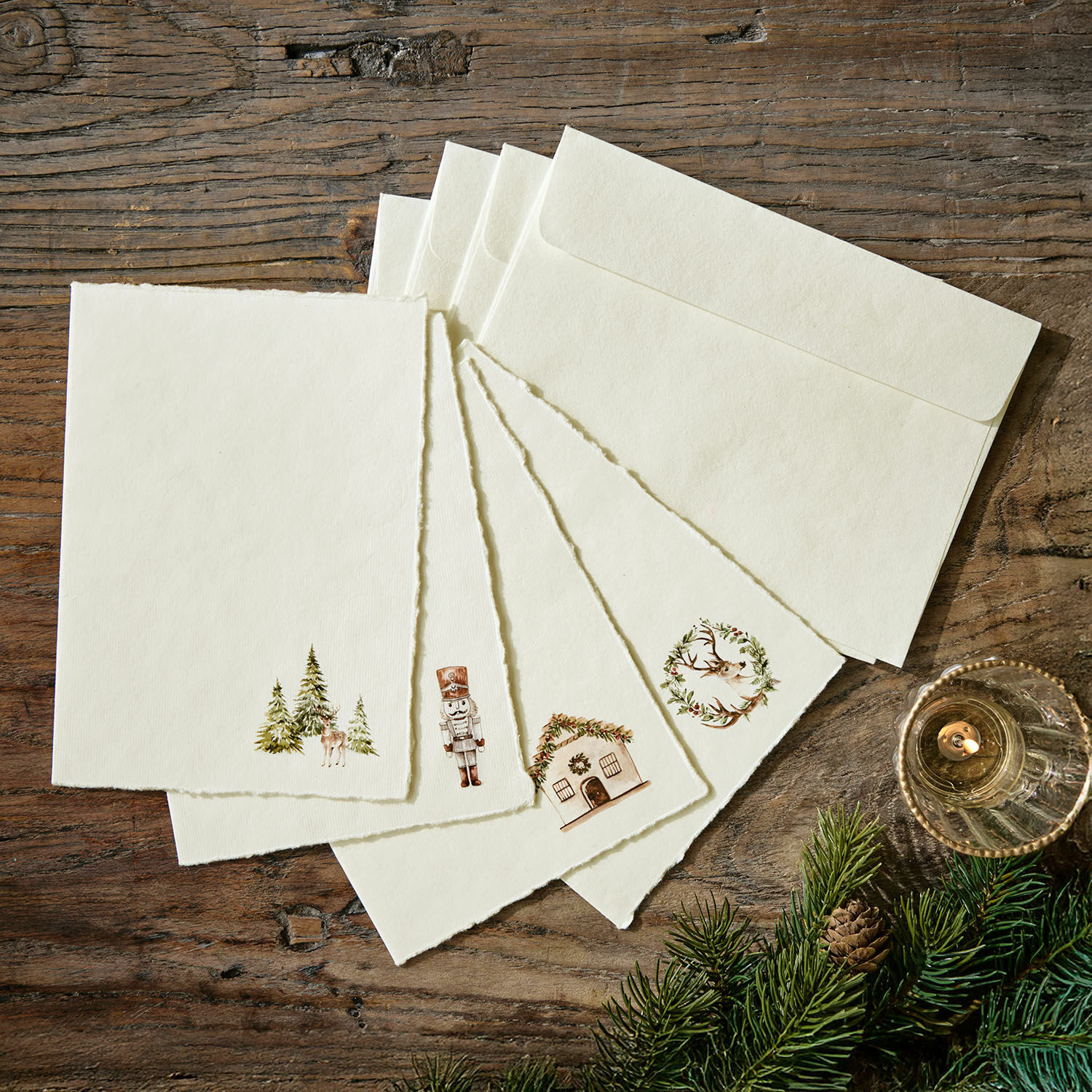 Set di 4 biglietti d'auguri Lorandis Set di carte e buste color crema con motivi natalizi su tavolo in legno con rami di abete
