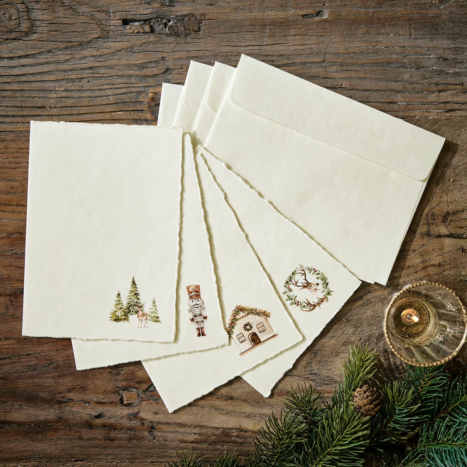 Set di 4 biglietti d'auguri Lorandis Set di carte e buste color crema con motivi natalizi su tavolo in legno con rami di abete