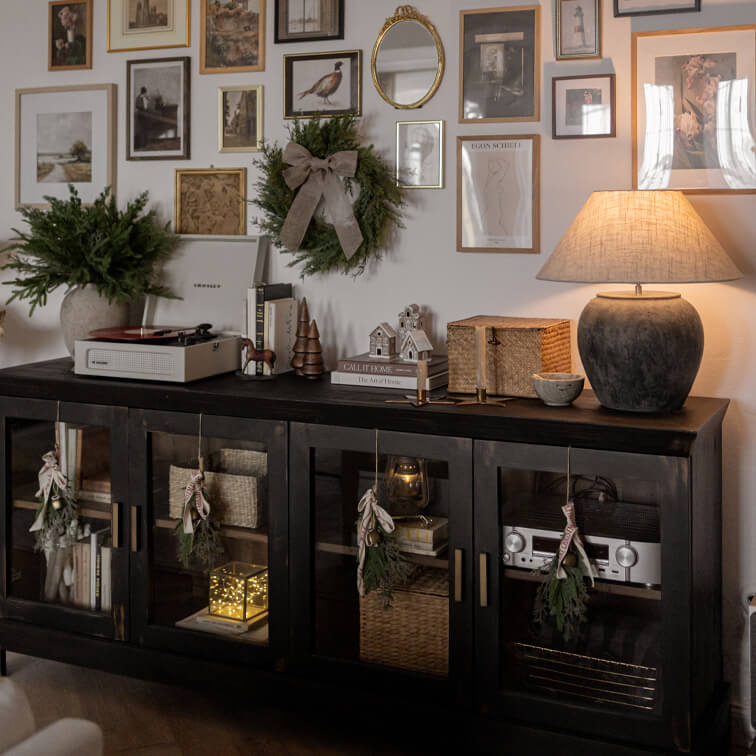 Madia in legno nero con ante in vetro, decorazioni natalizie e lampada in ceramica in soggiorno accogliente