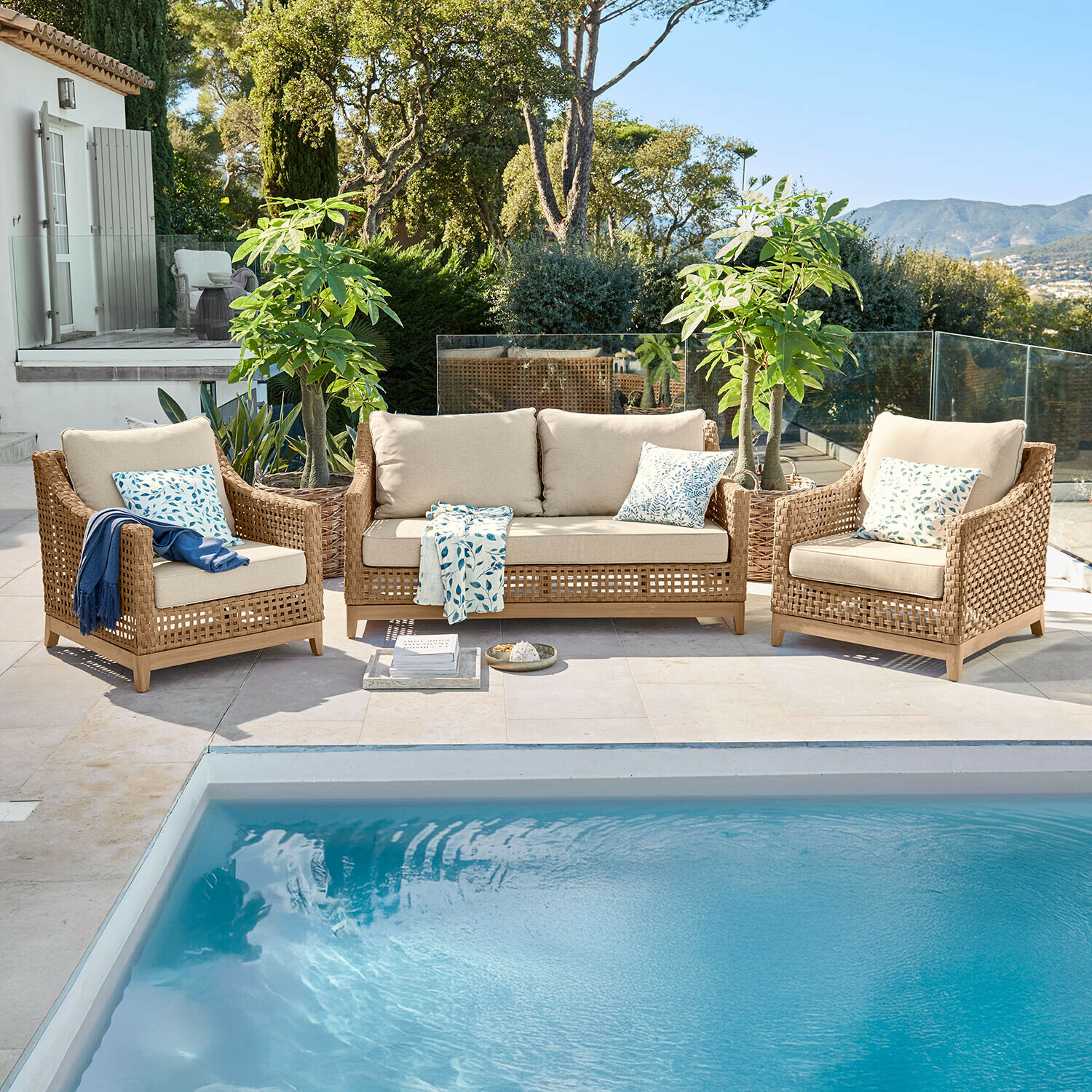 Set divano e poltrone Isolara Set di mobili da giardino in rattan marrone con cuscini beige accanto a una piscina