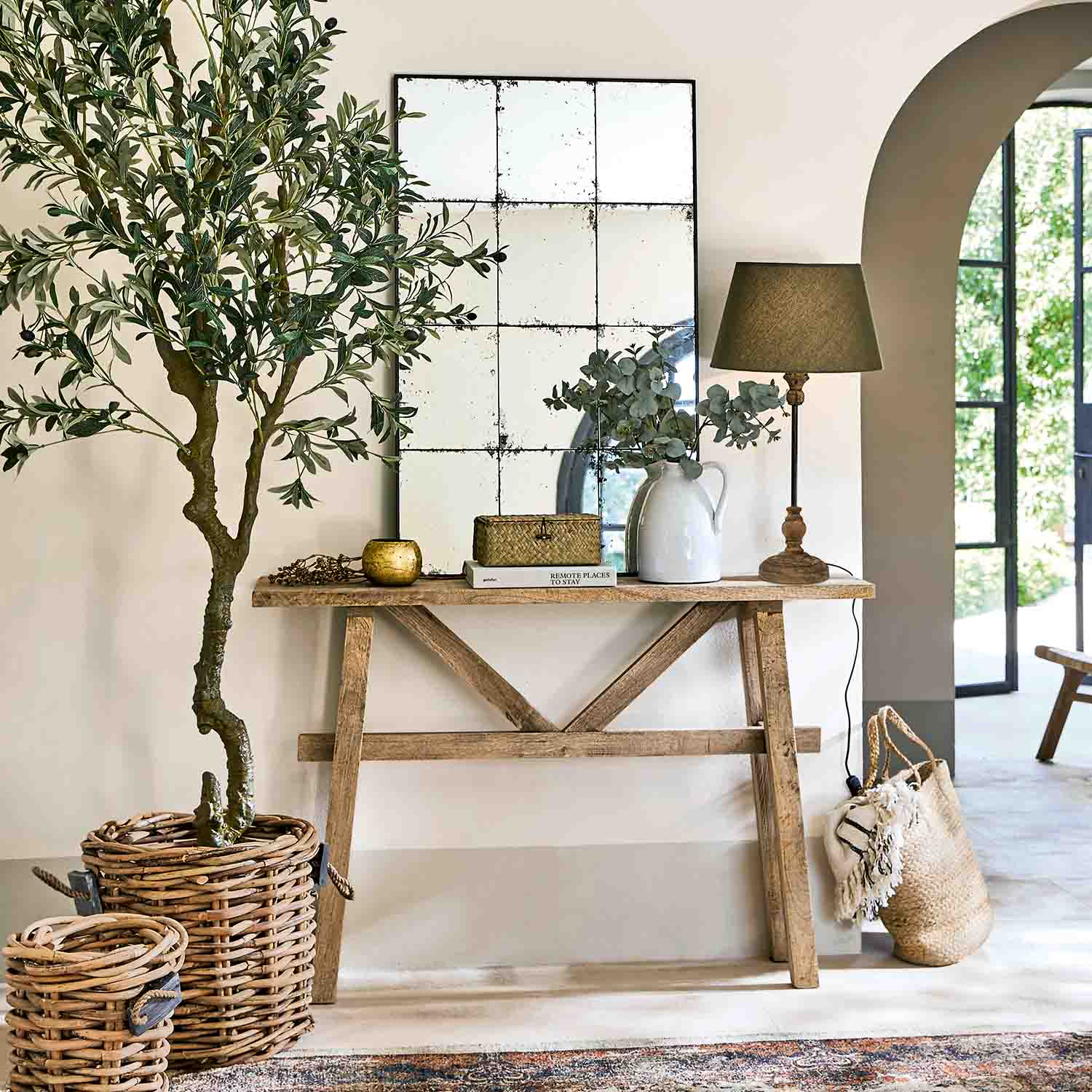 Consolle in legno con specchio, lampada e decorazioni in vimini in ambiente luminoso e naturale