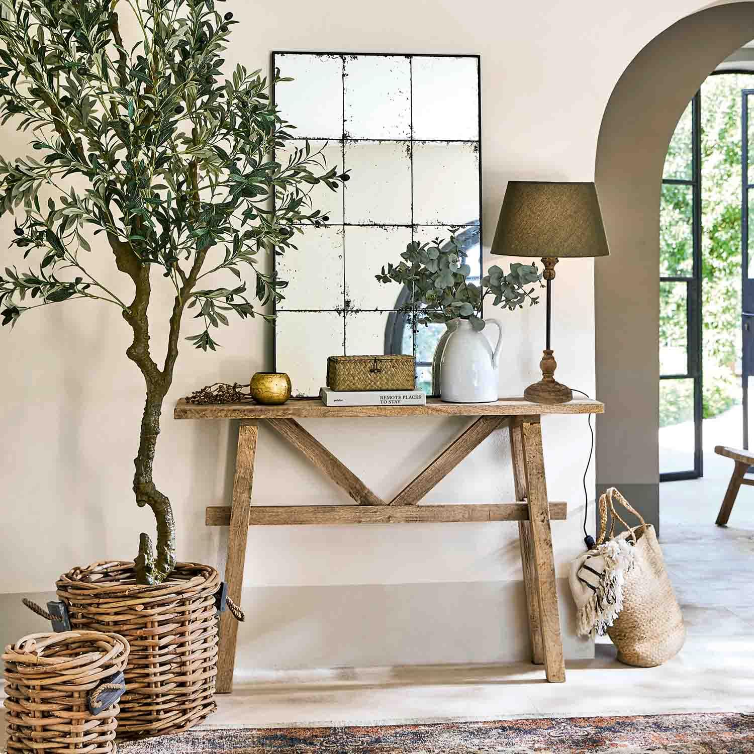 Consolle in legno con specchio, lampada e decorazioni in vimini in ambiente luminoso e naturale