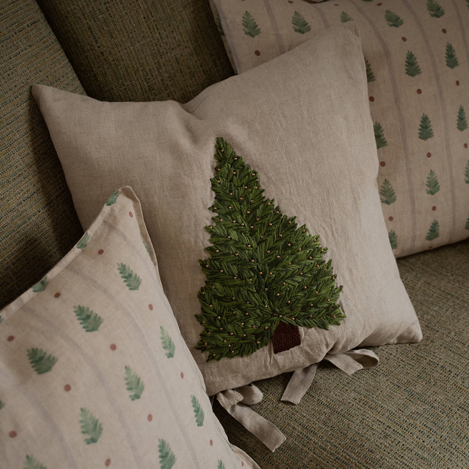 Cuscino beige in lino con albero verde ricamato e perline dorate su divano