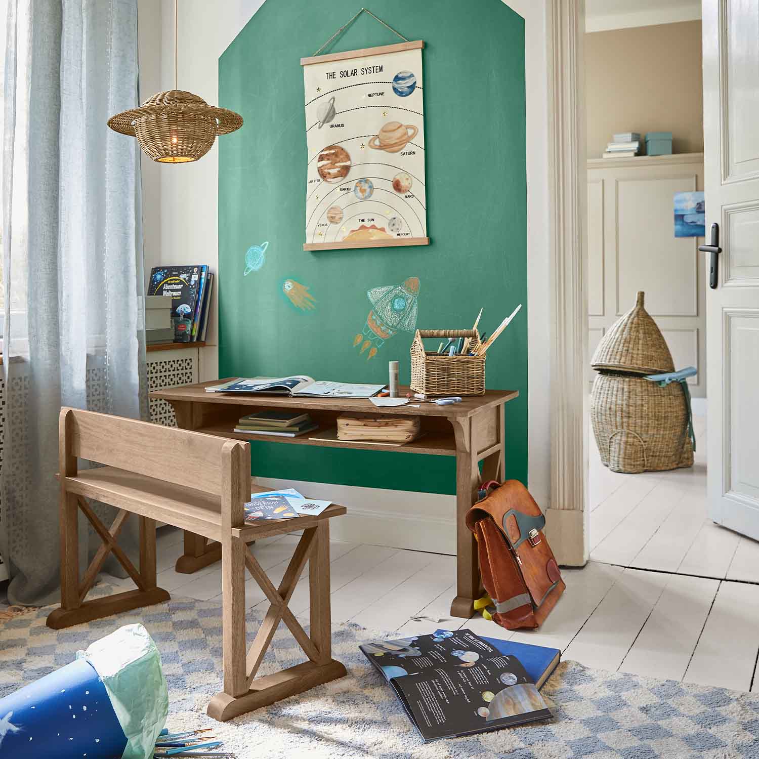 Scrivania e panca in legno in camera bambini con parete verde e poster del sistema solare
