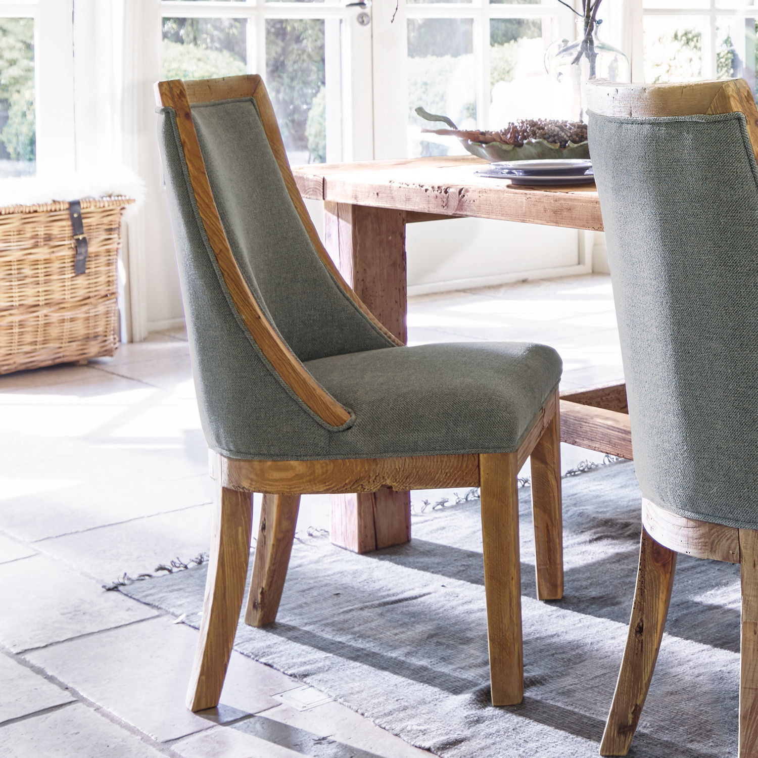 Sedia Oteley Sedia da pranzo in legno e tessuto grigio in ambiente luminoso con tappeto naturale