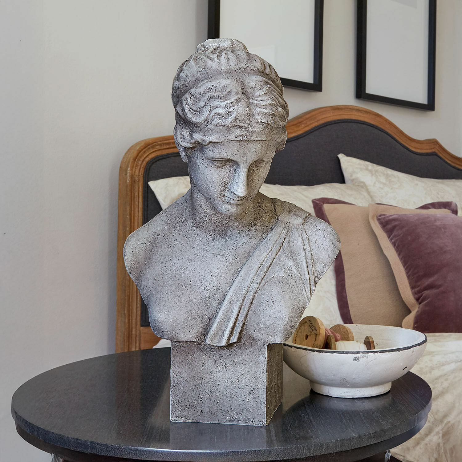 Busto Castolio Busto in pietra grigia su tavolo nero in interno elegante con cuscini decorativi
